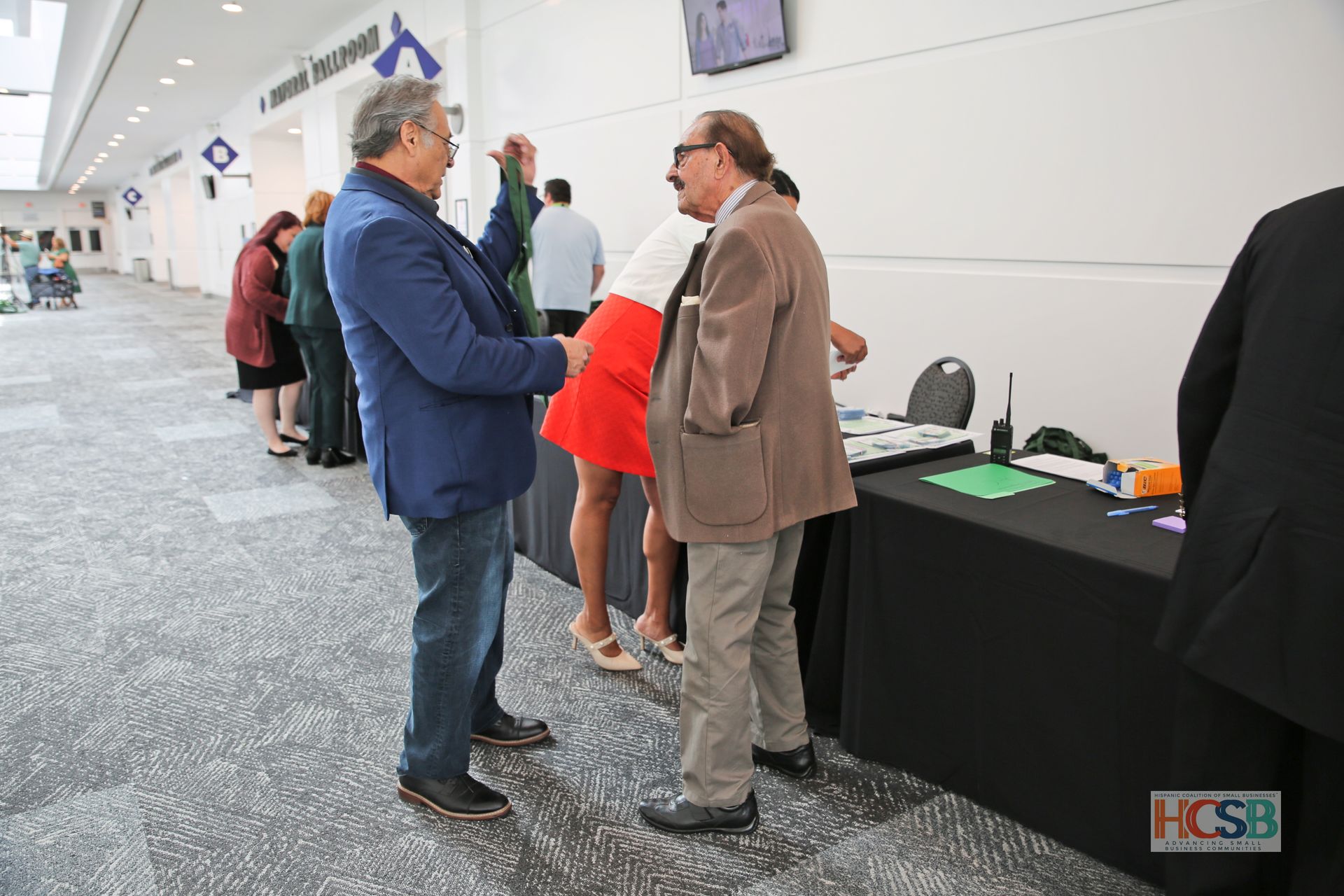 A group of people are standing in a hallway talking to each other.