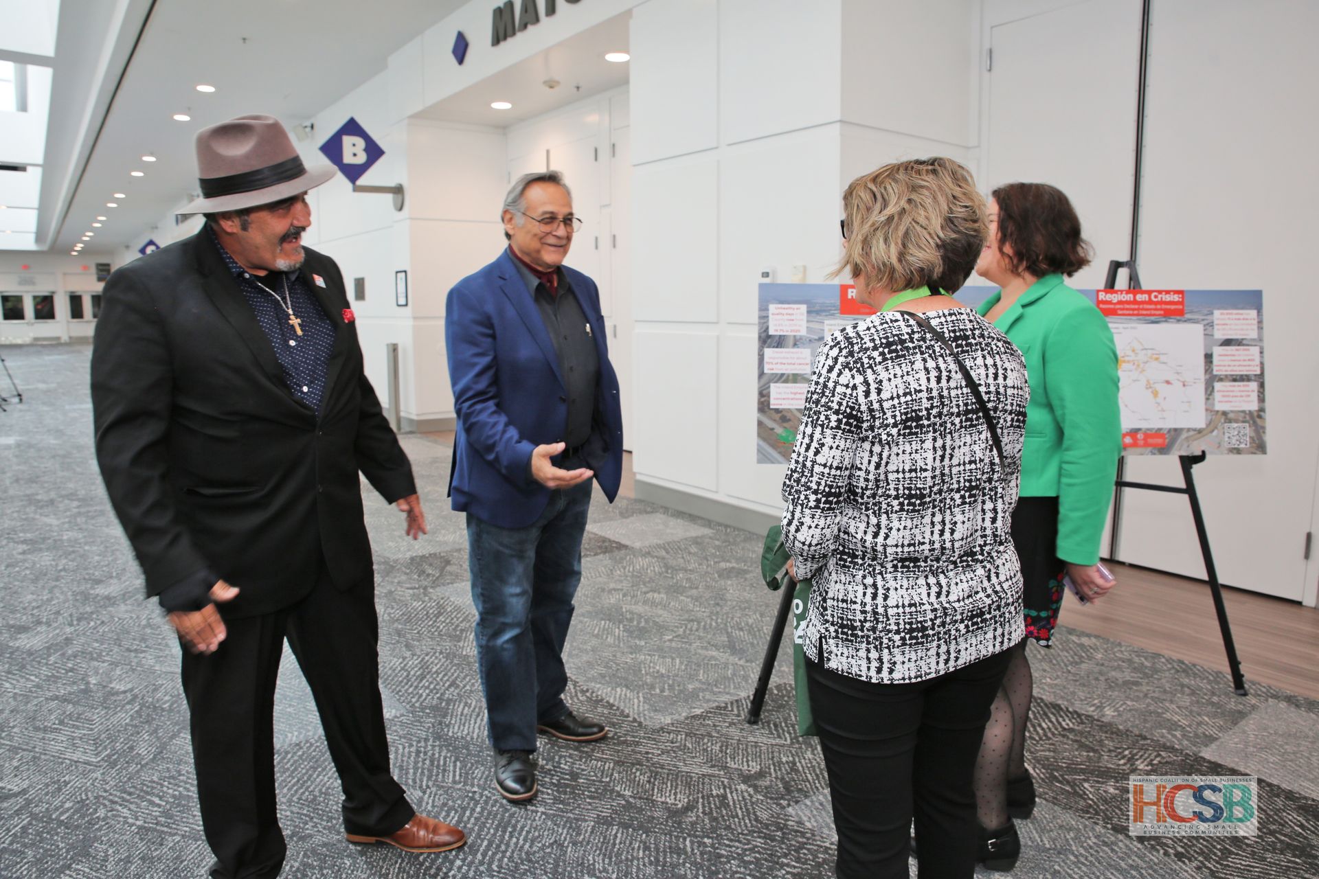 A group of people are standing in a hallway talking to each other