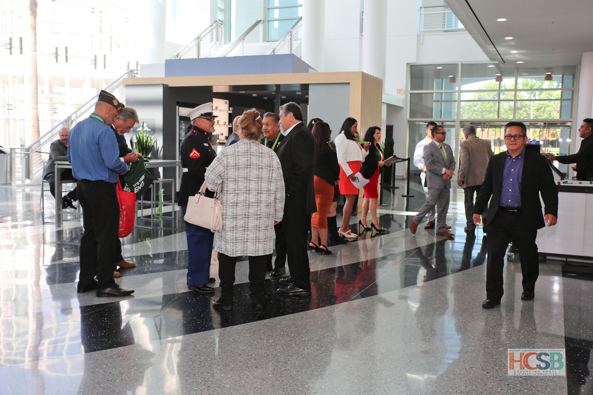 A group of people are standing in a lobby talking to each other.