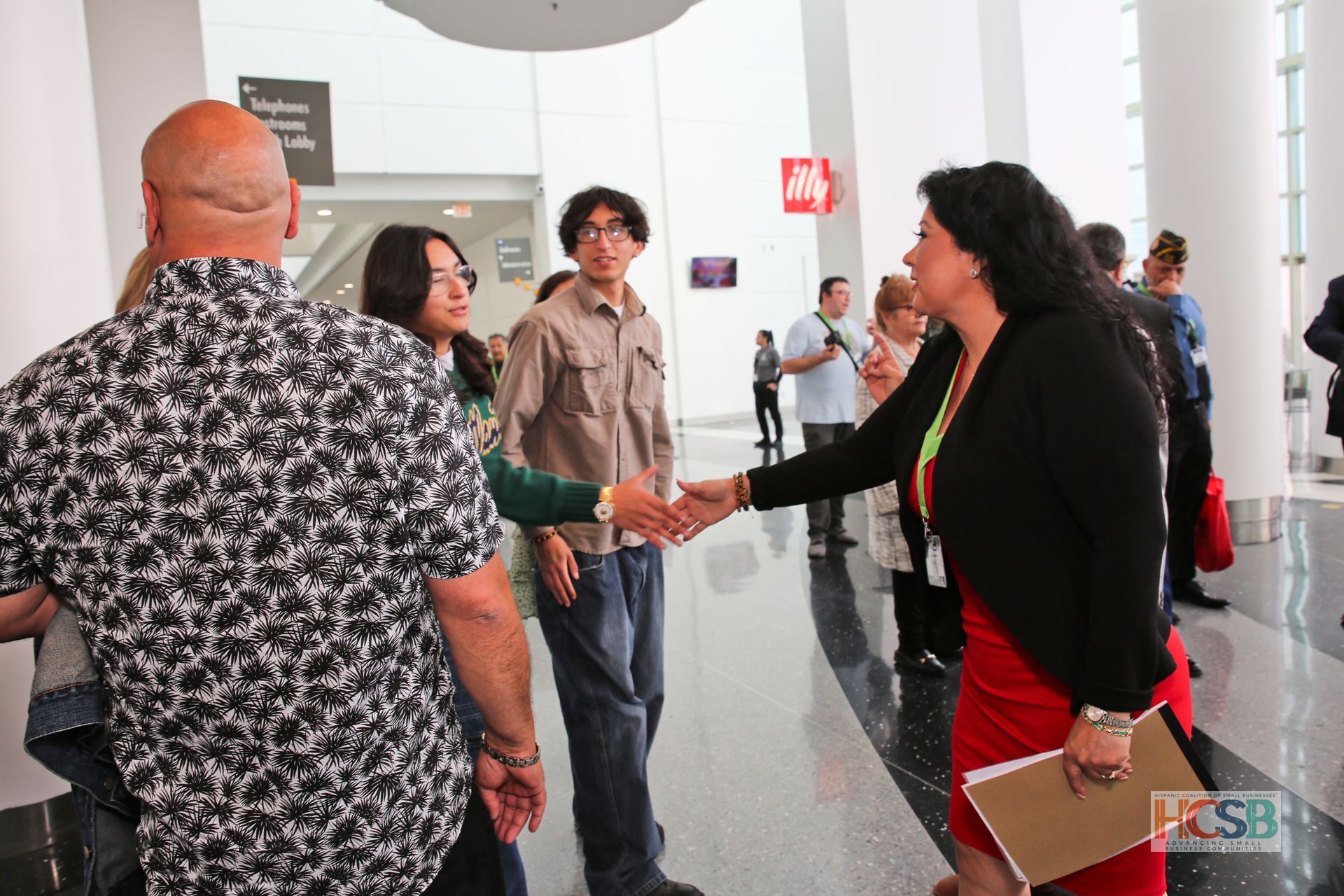 A woman in a red dress shakes hands with a man in a black shirt