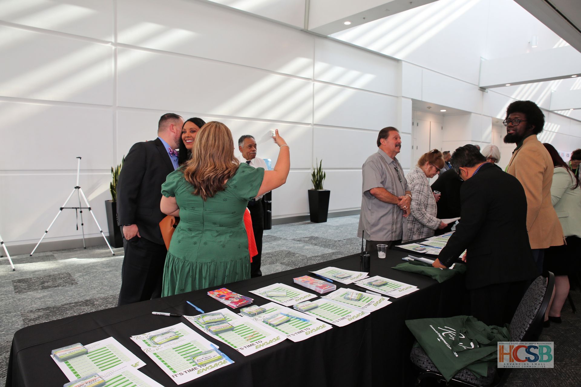 A group of people are standing around a table that says hcsb on it