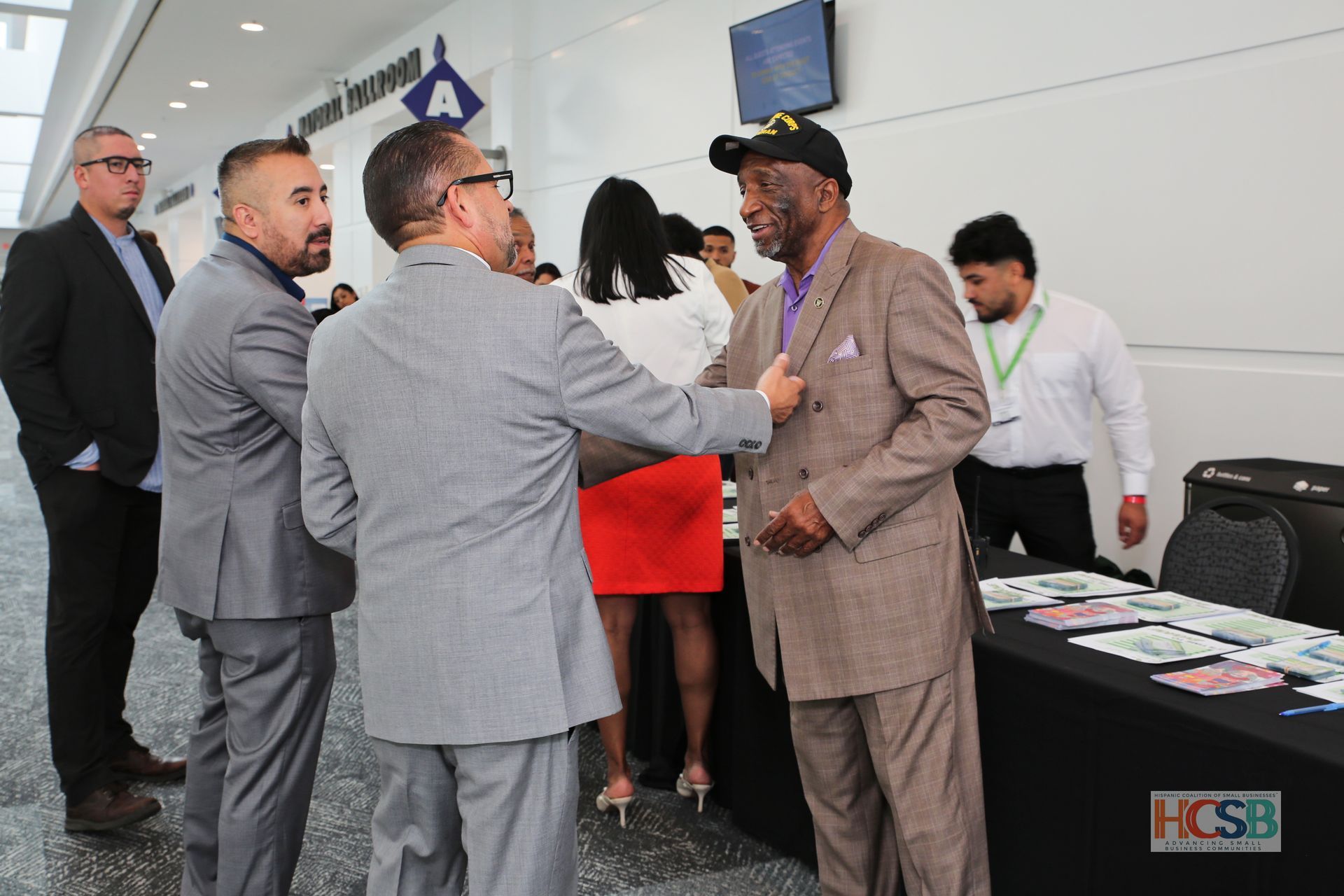 A group of men are standing around a table and talking to each other