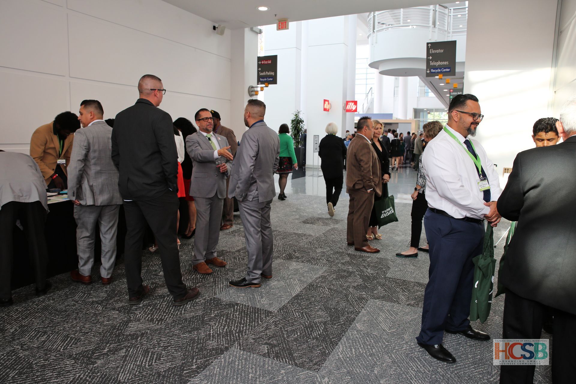 A group of people are standing in a hallway talking to each other.