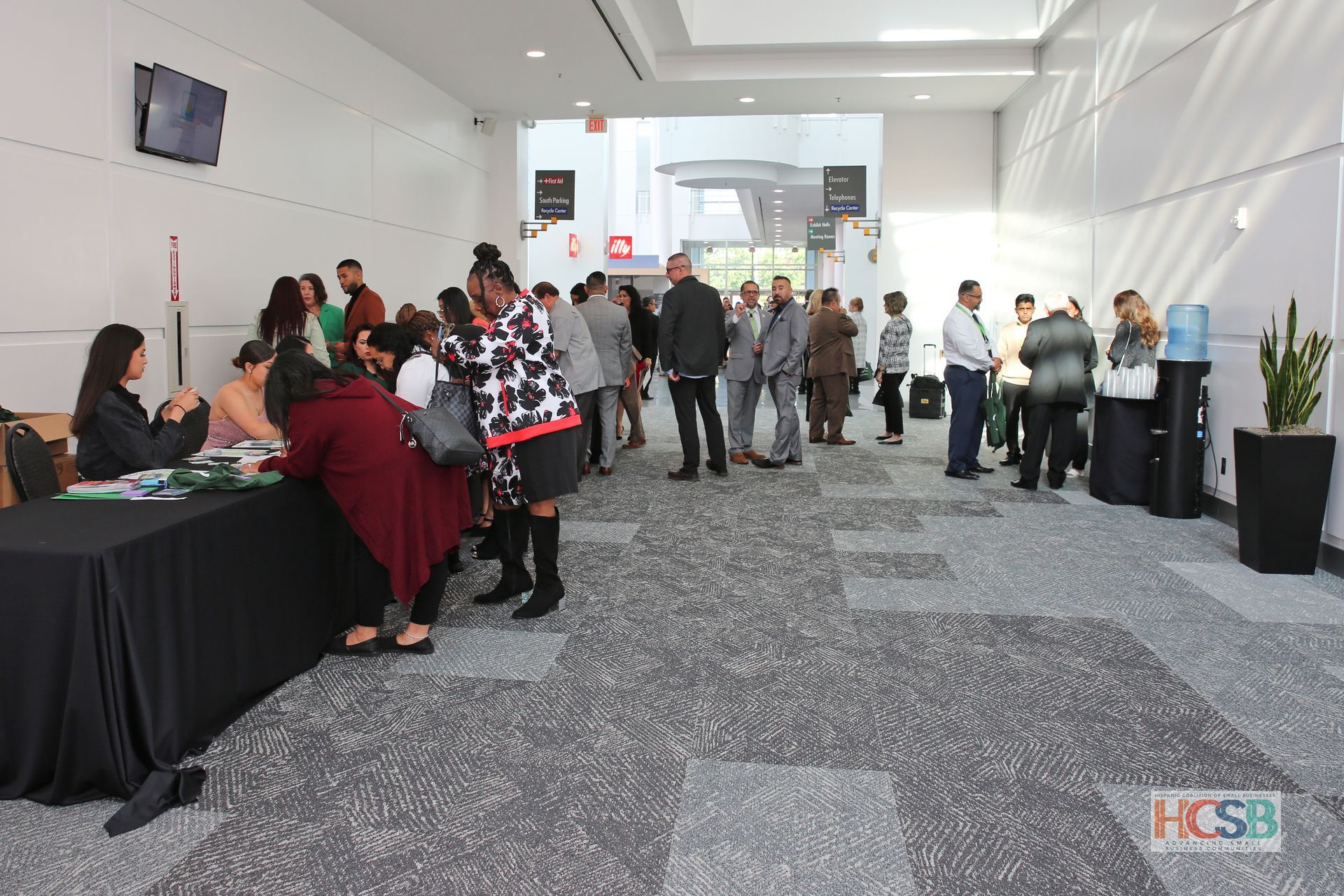 A group of people are standing in a hallway with a sign that says hcsb