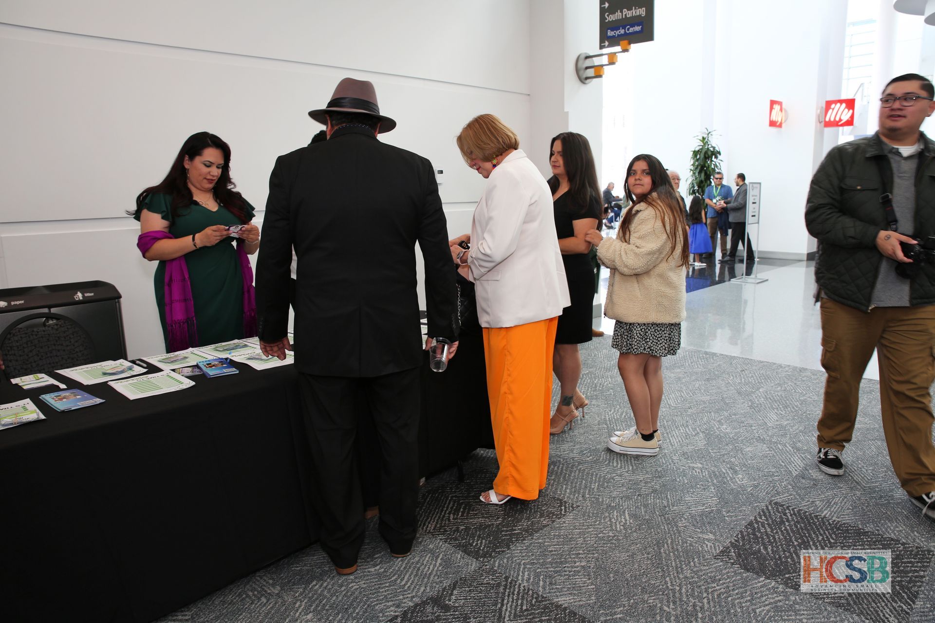 A group of people are standing around a table in a hallway.