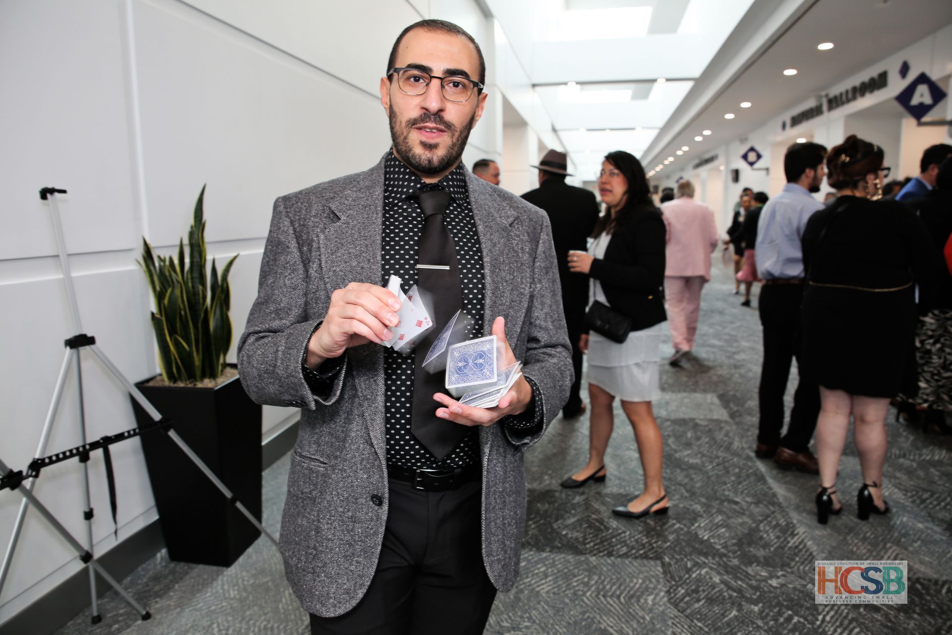 A man in a suit is holding a deck of playing cards