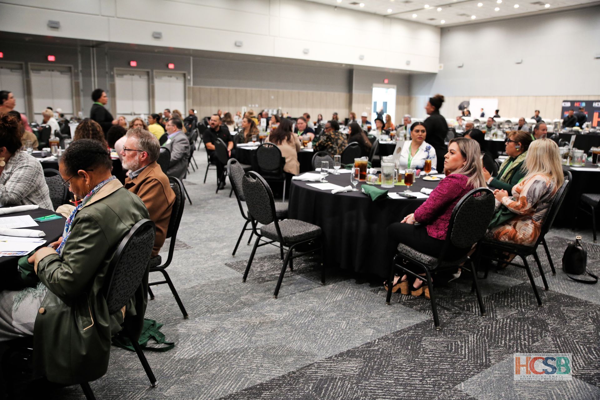 A large group of people are sitting at tables in a large room.