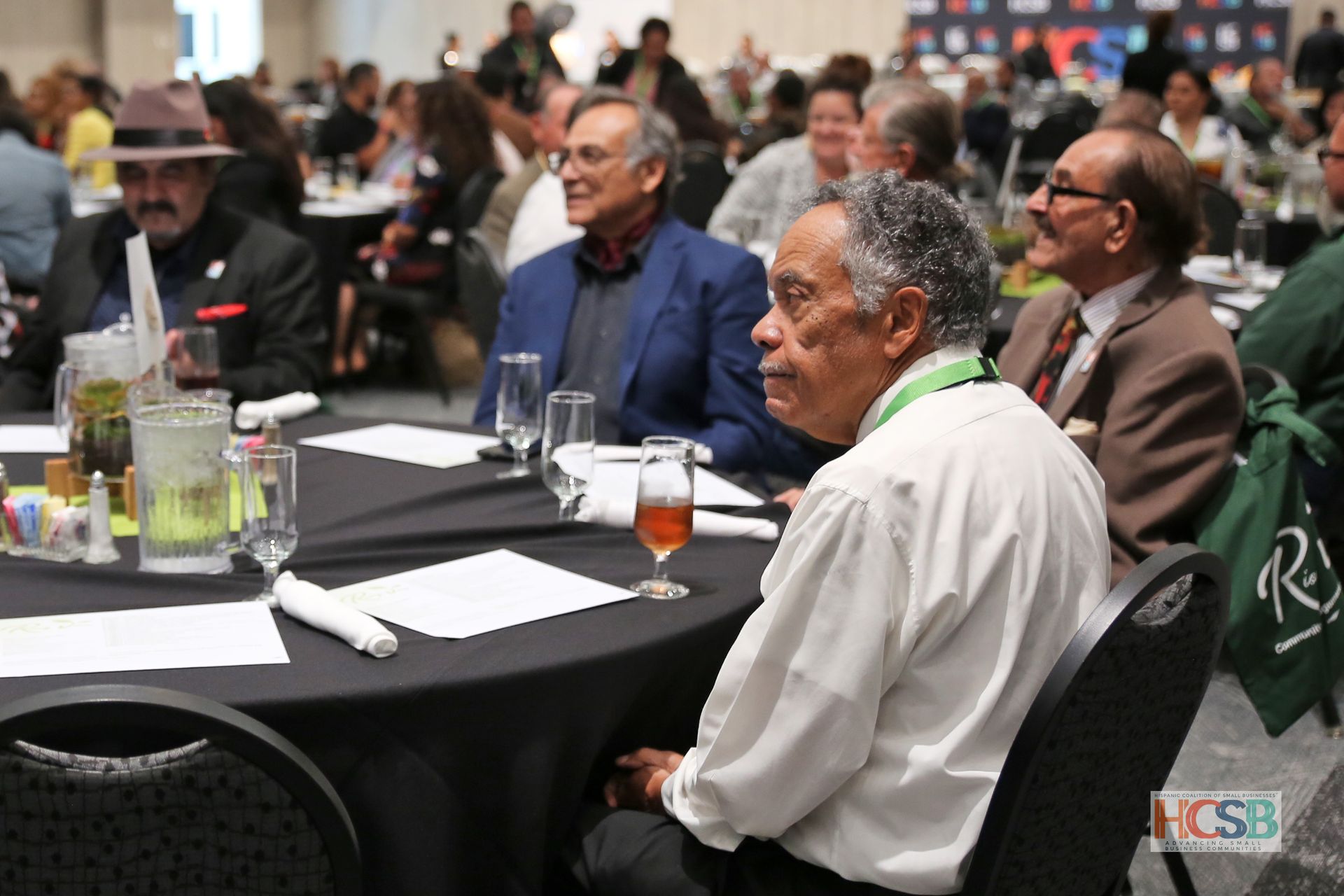 A man sits at a table with a glass of wine