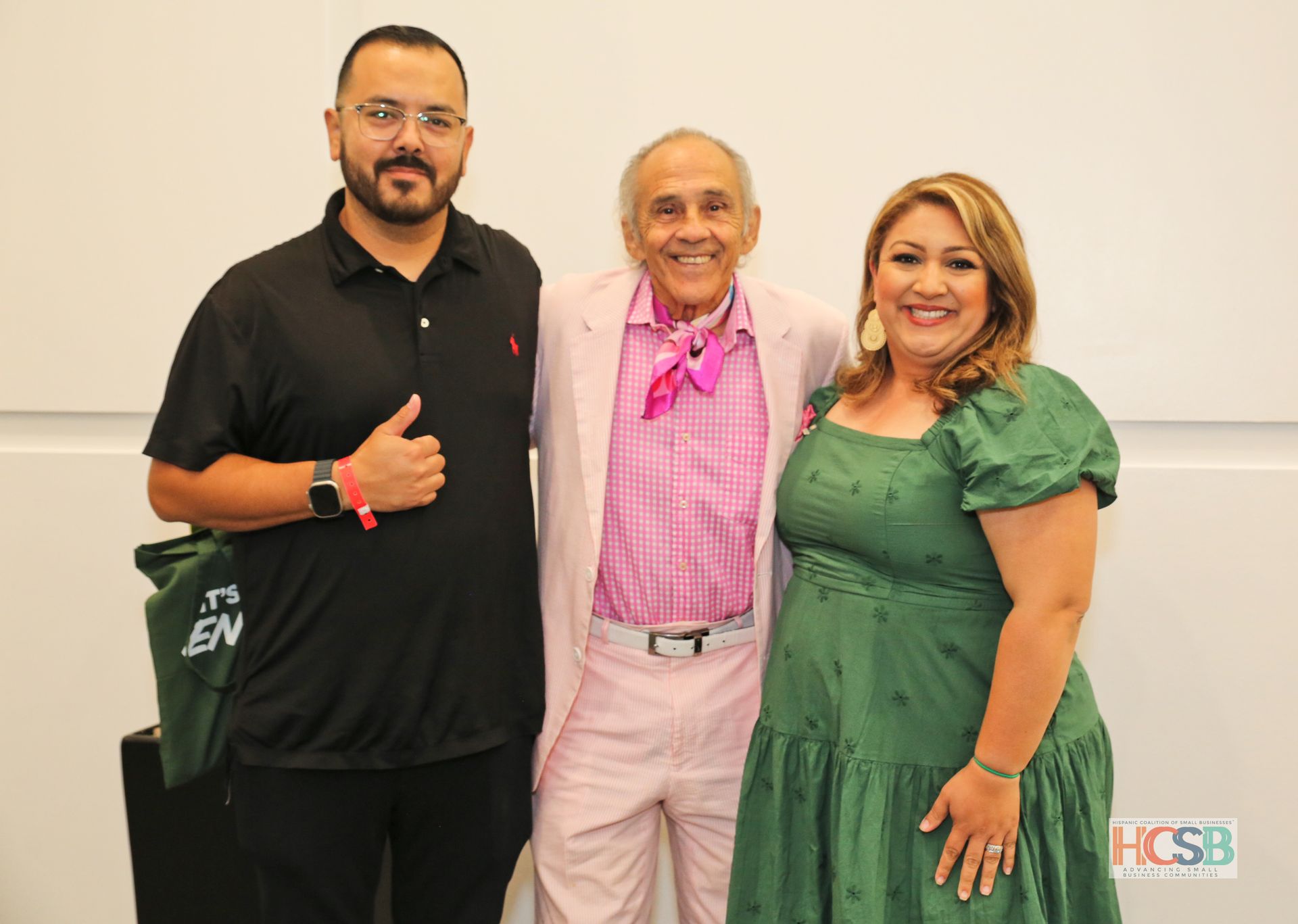A man in a pink suit and a woman in a green dress are posing for a picture.