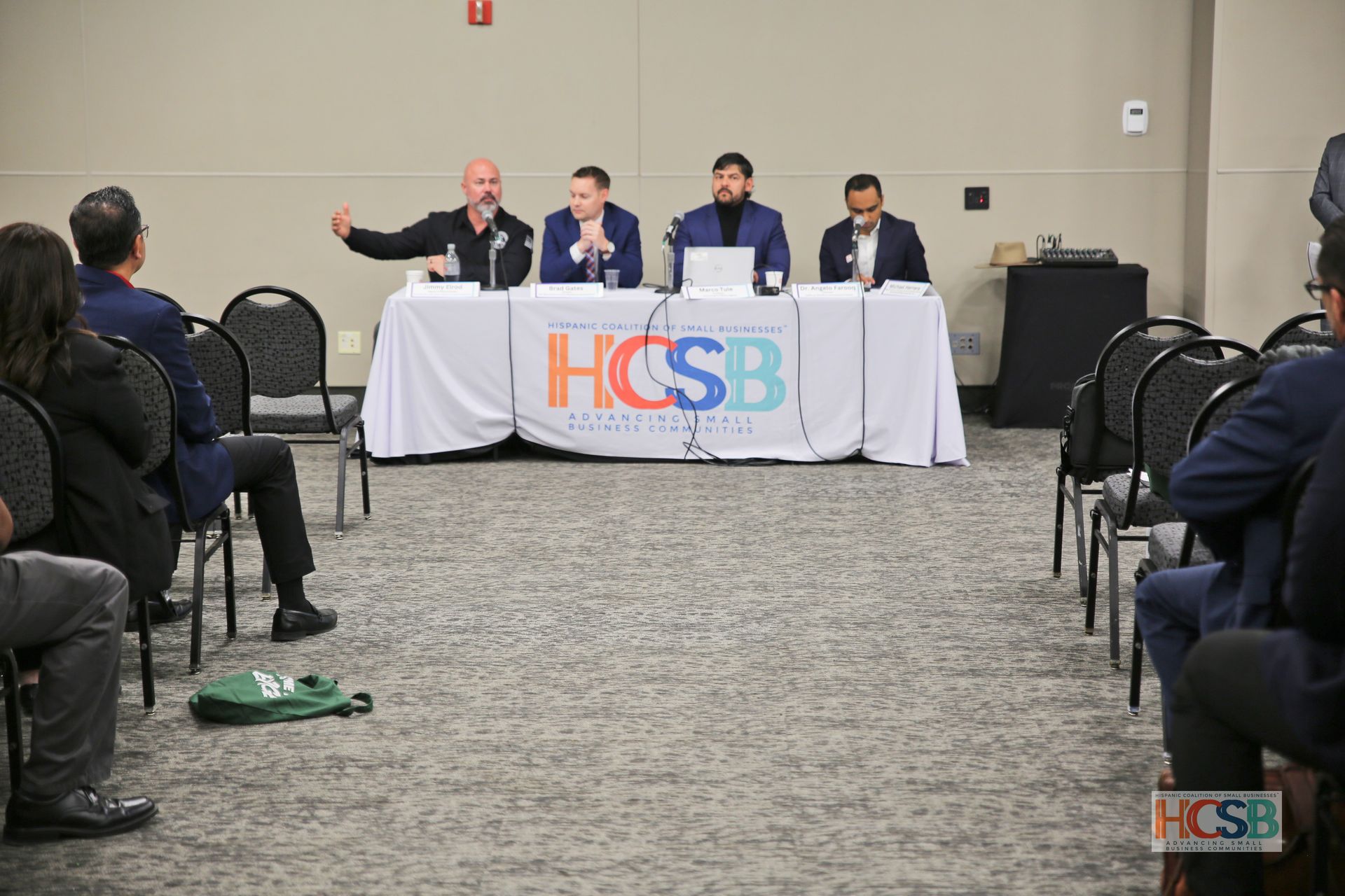 A group of people are sitting at a table with a sign that says hcsb on it.