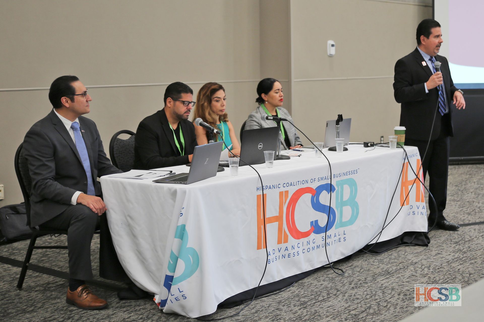 A group of people sitting at a table with a sign that says hcsb