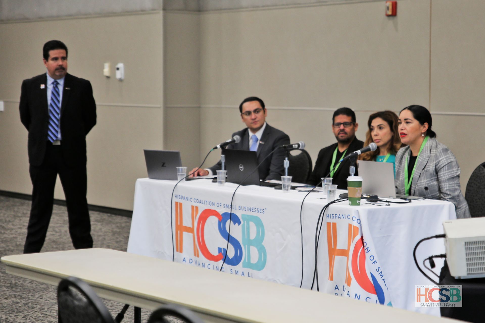 A group of people sitting at a table with a sign that says hcsb
