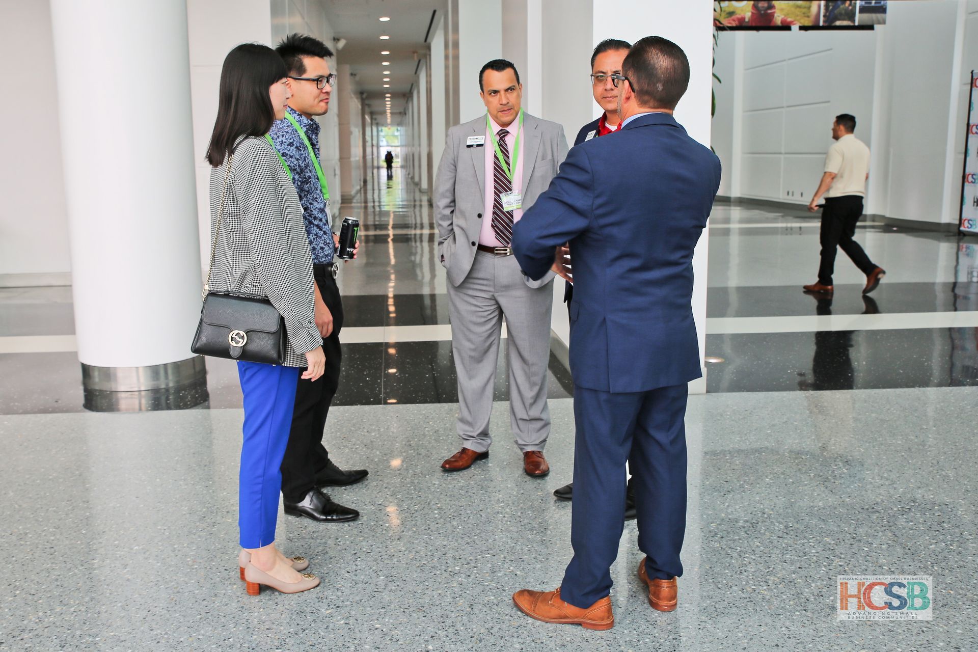 A group of people are standing in a hallway talking to each other.