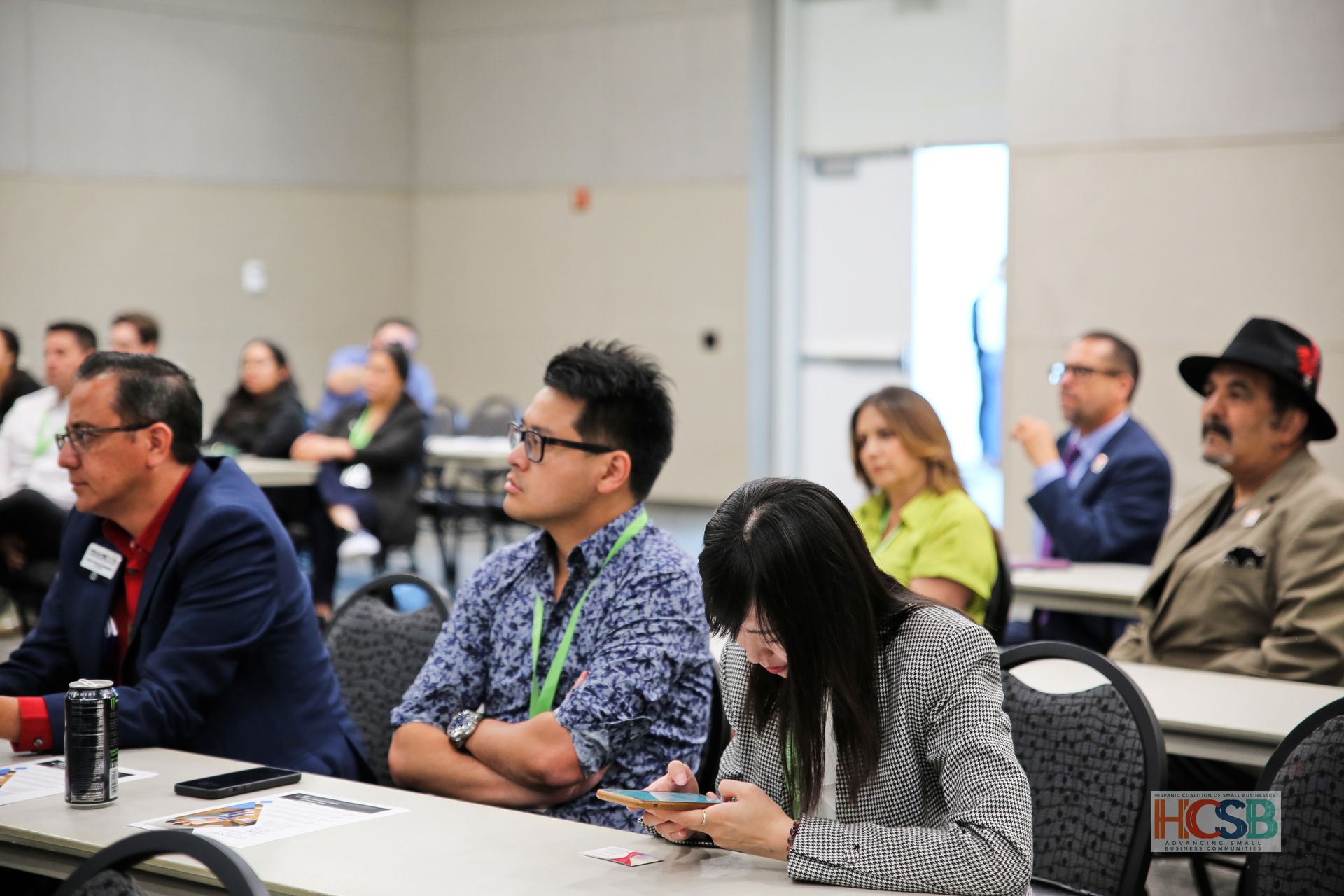 A group of people are sitting at tables in a conference room.