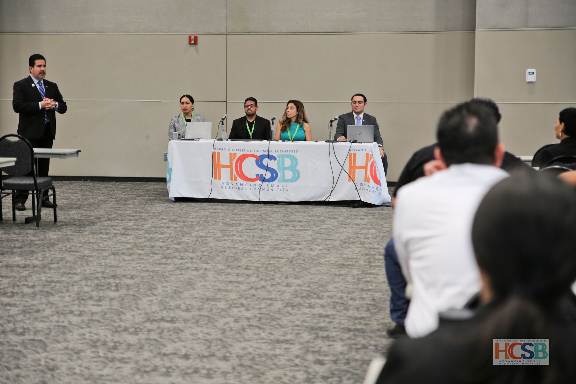 A group of people sitting at a table with a sign that says hcsb