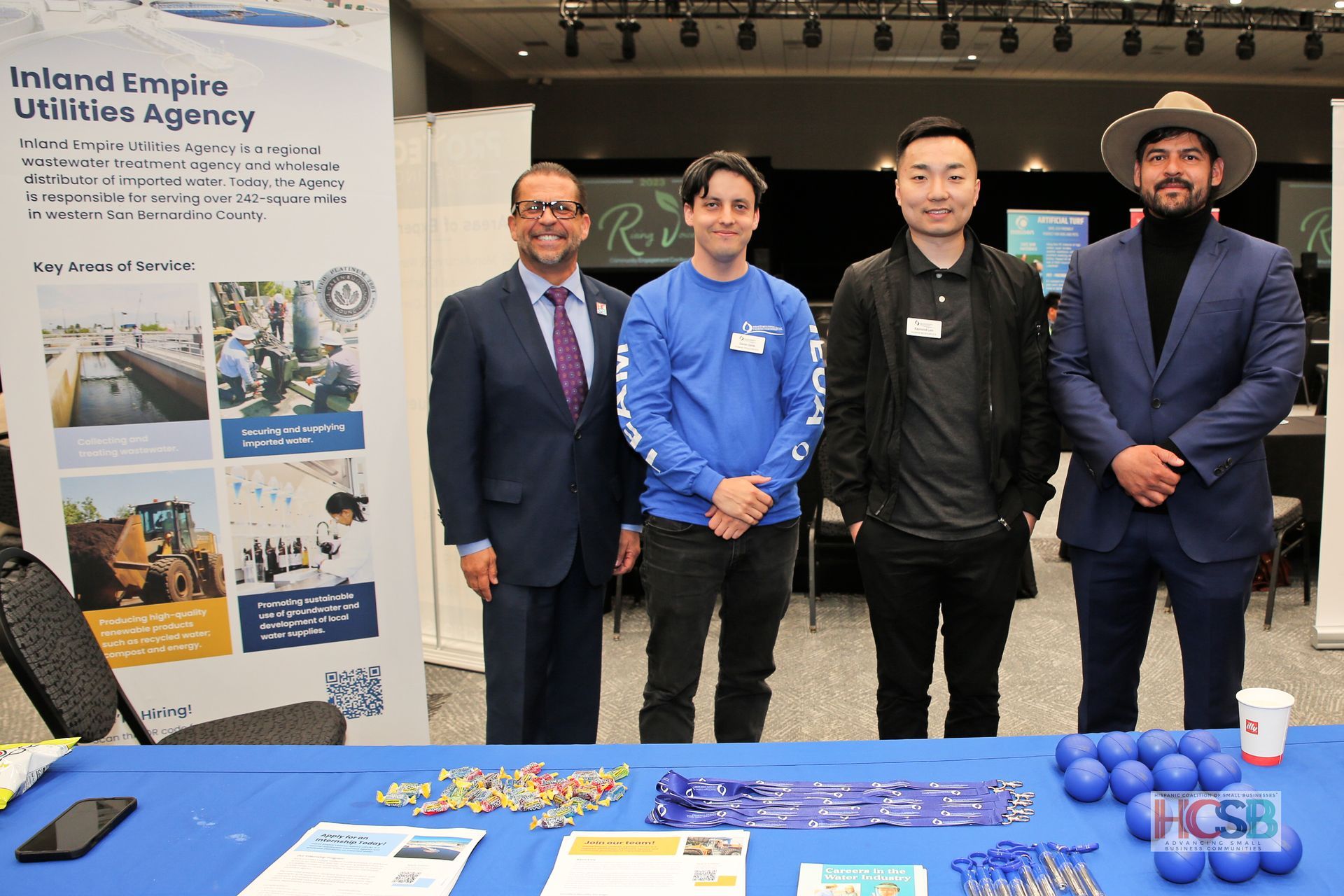 A group of men are standing around a table at a job fair.