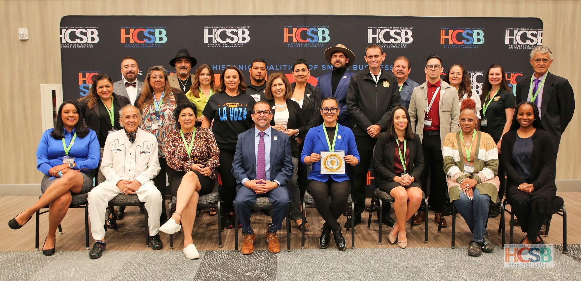 A group of people are posing for a picture in front of a wall.