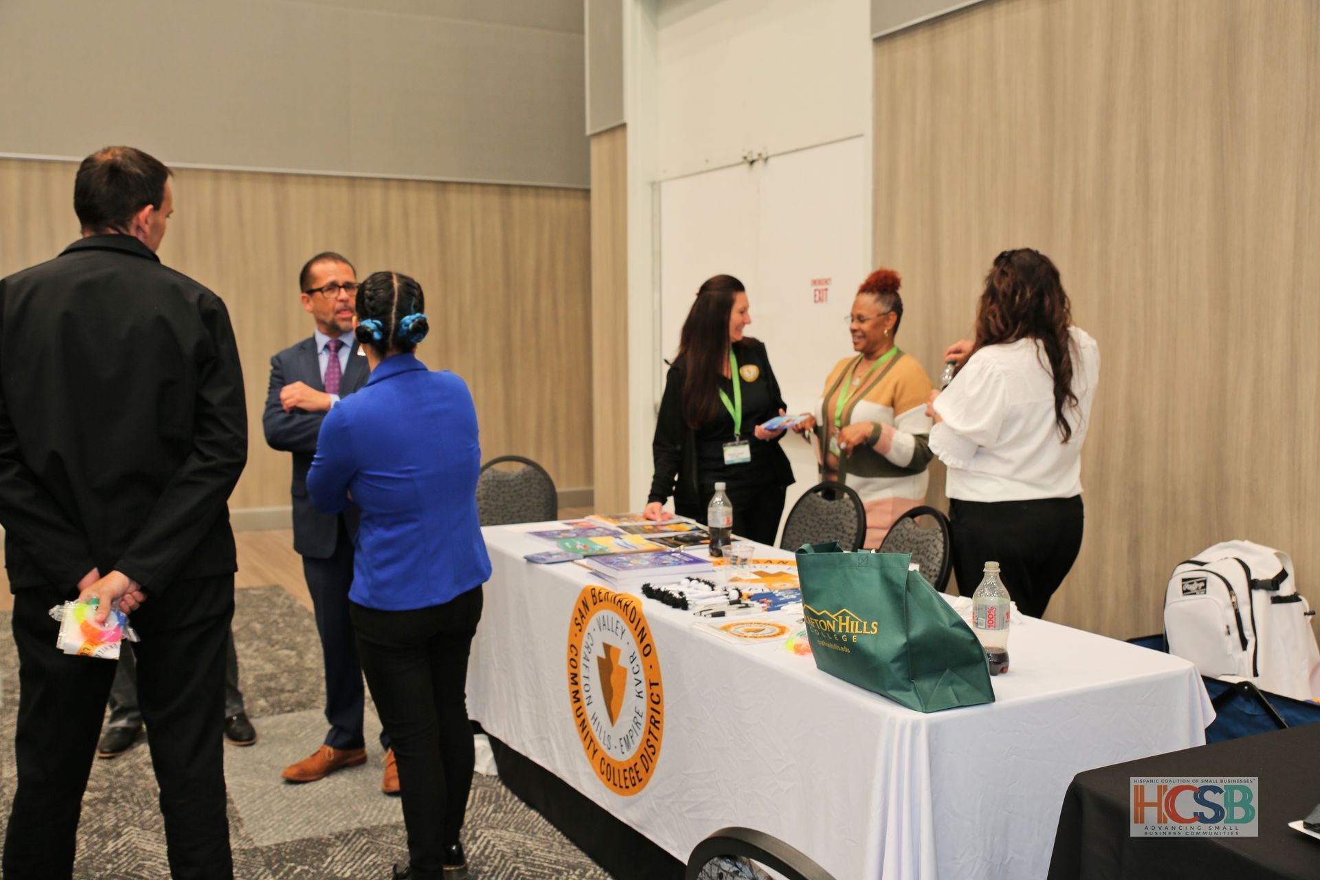 A group of people are standing around a table talking to each other.