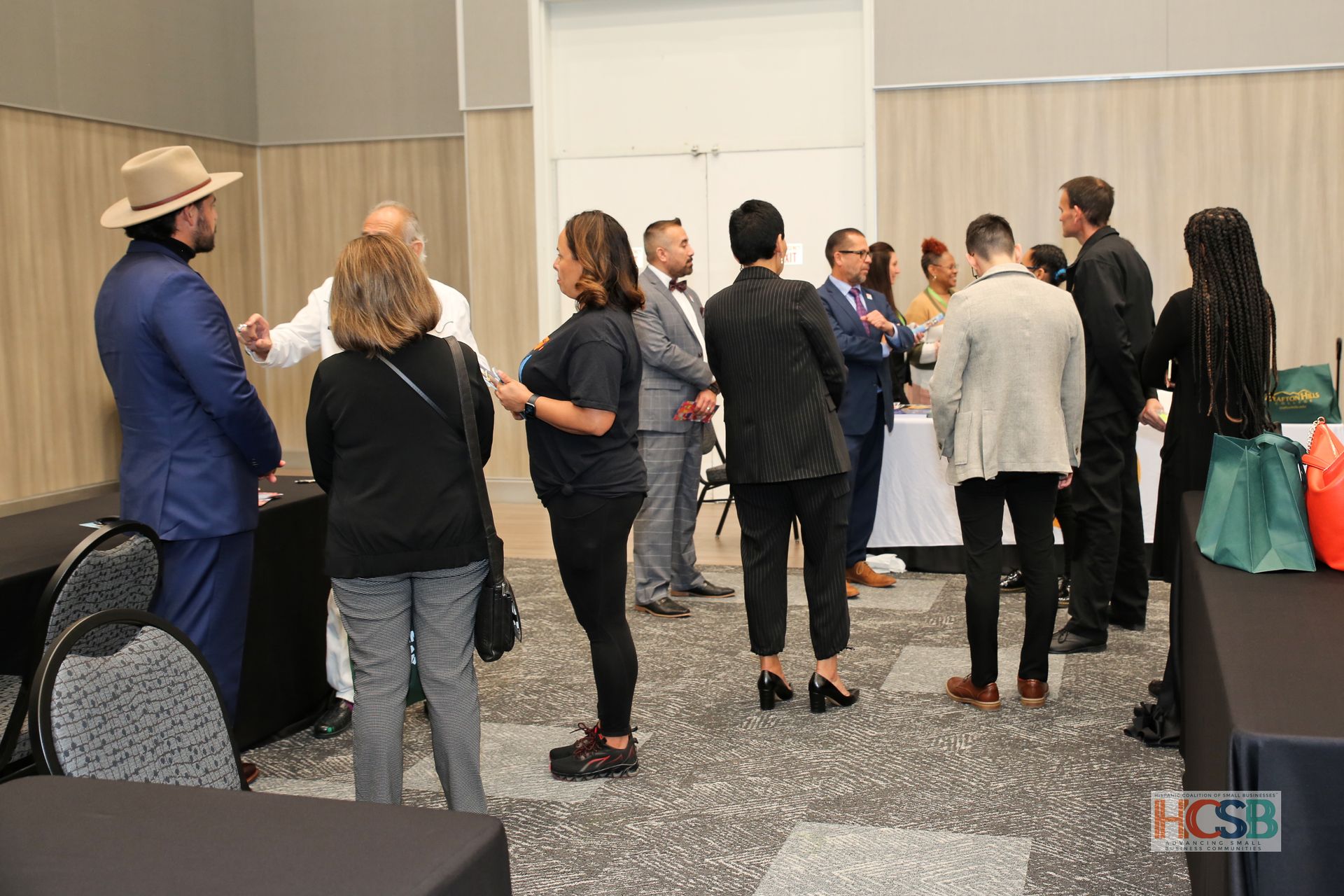A group of people are standing in a room talking to each other.