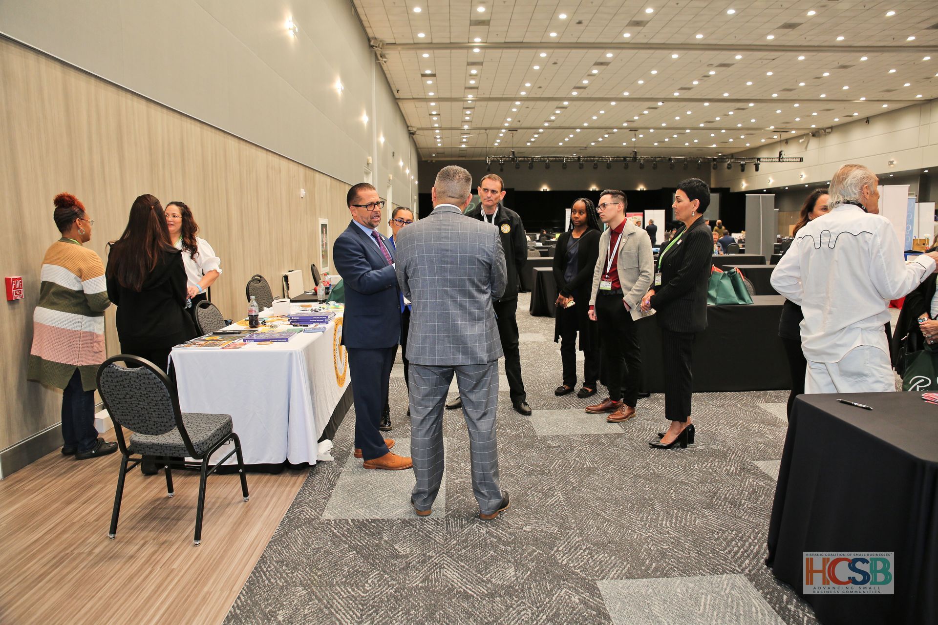 A group of people are standing in a large room talking to each other.