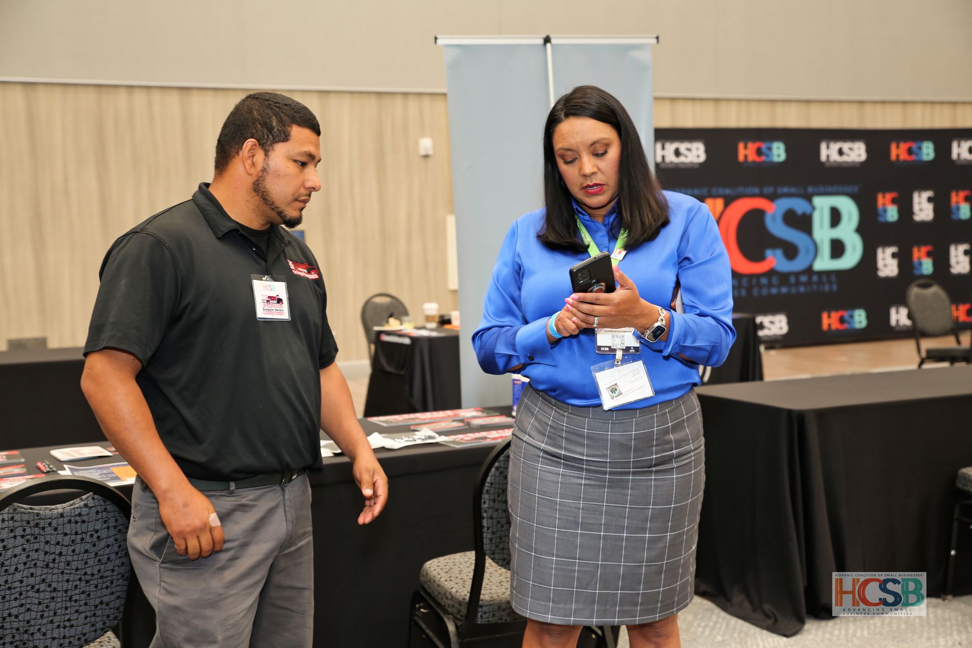 A man and a woman are standing next to each other looking at a cell phone.