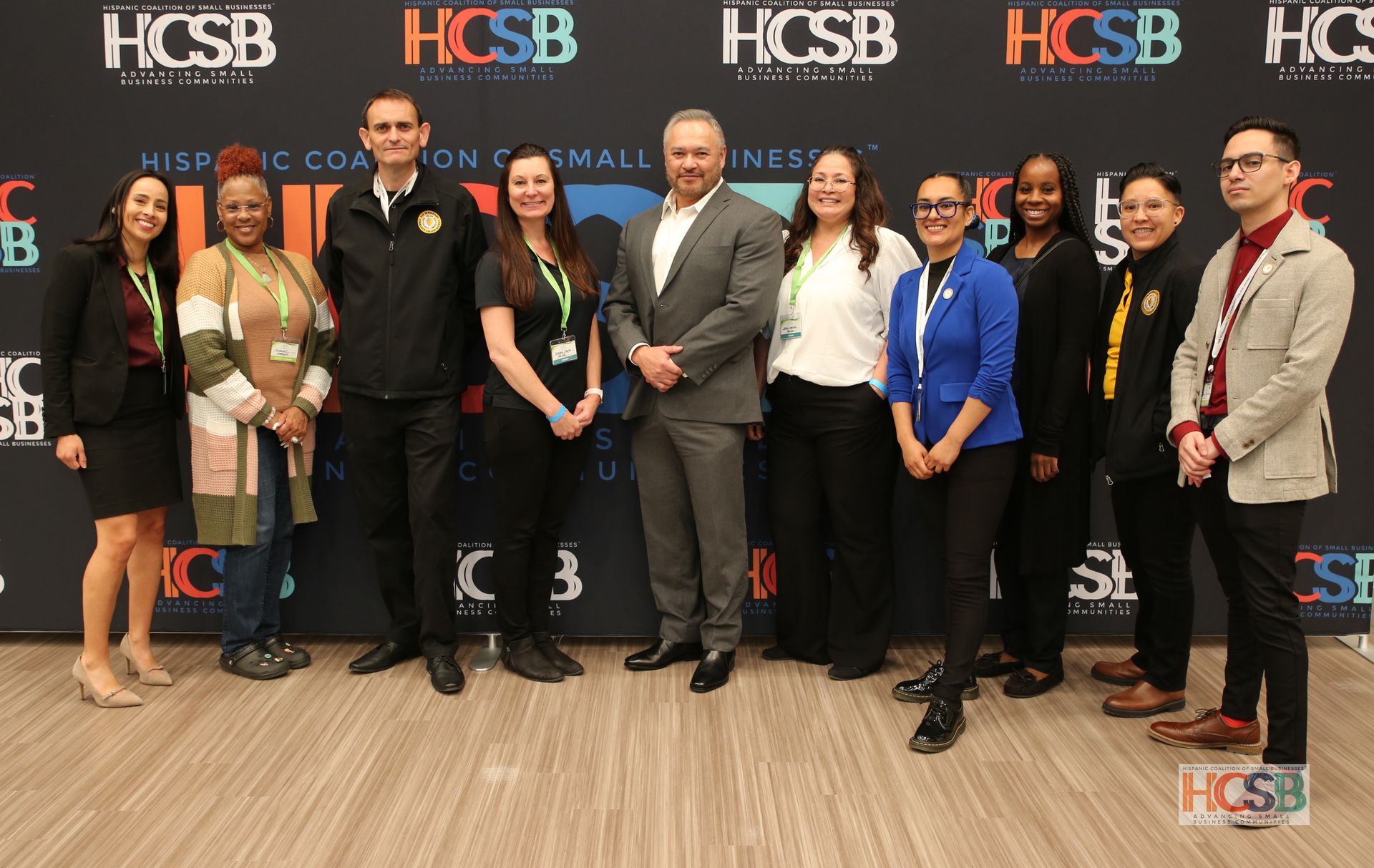 A group of people are posing for a picture in front of a hcsb banner.