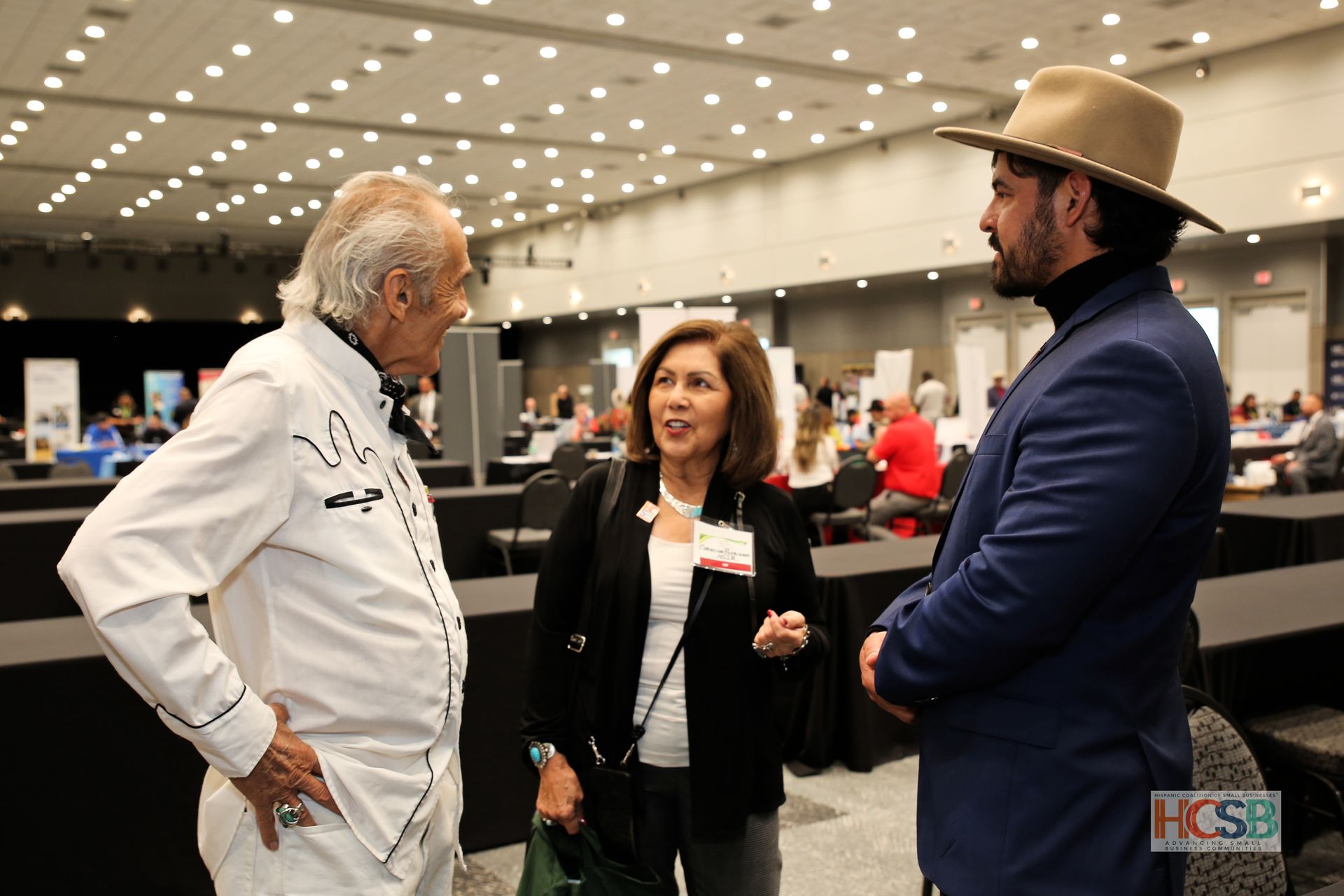 A group of people are standing in a room talking to each other.