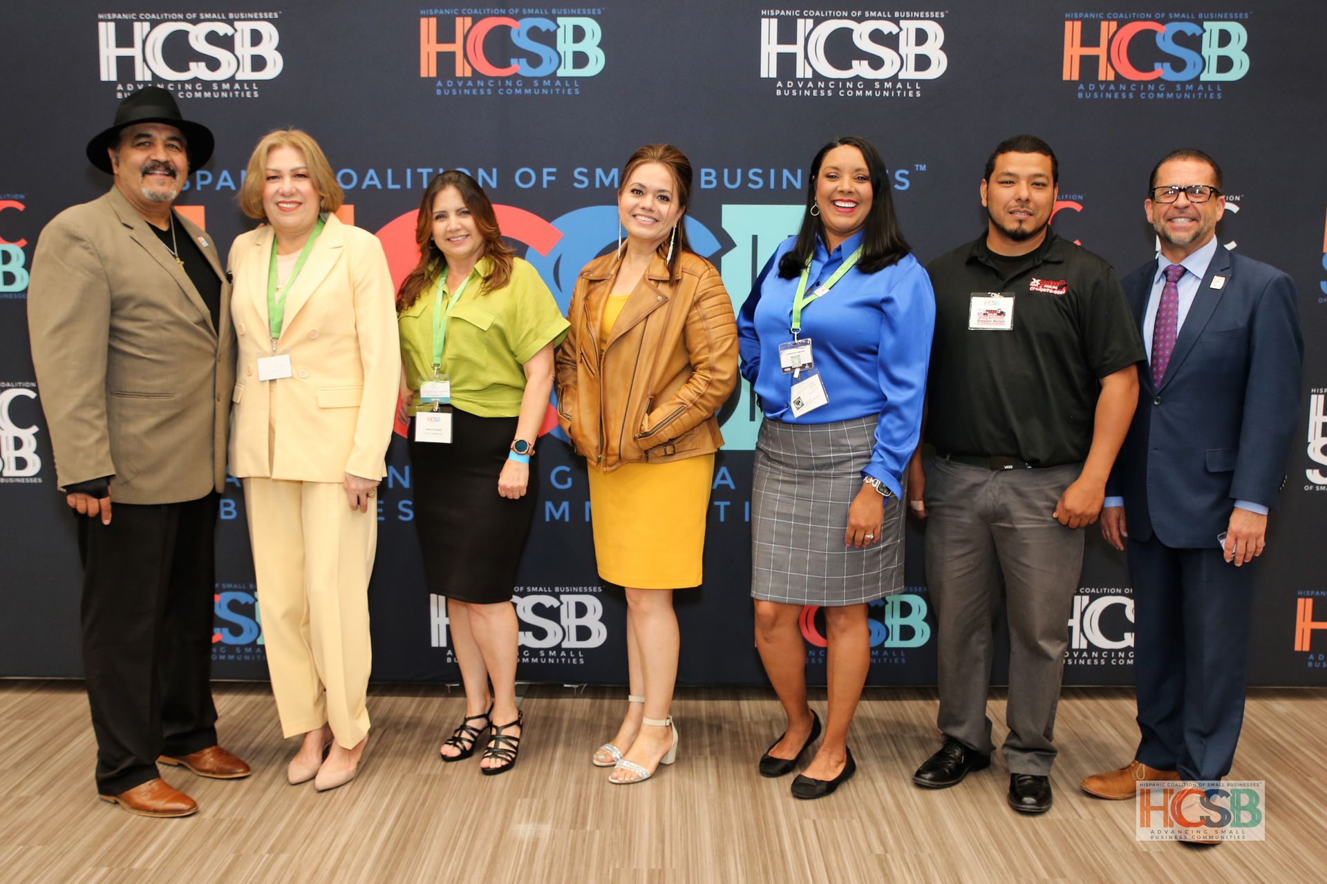 A group of people are posing for a picture in front of a hcsb banner.