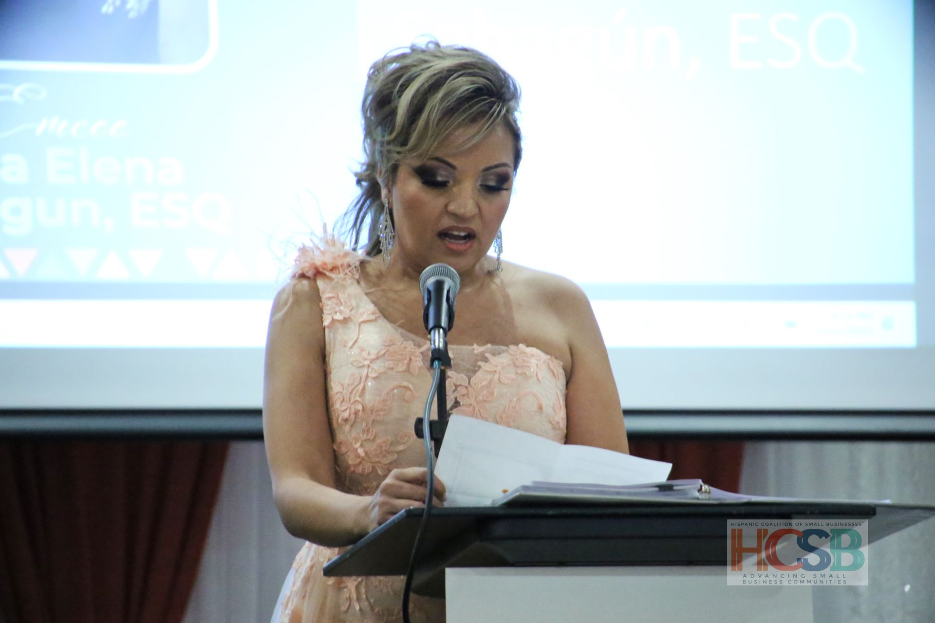 A woman in a dress is standing at a podium giving a speech.