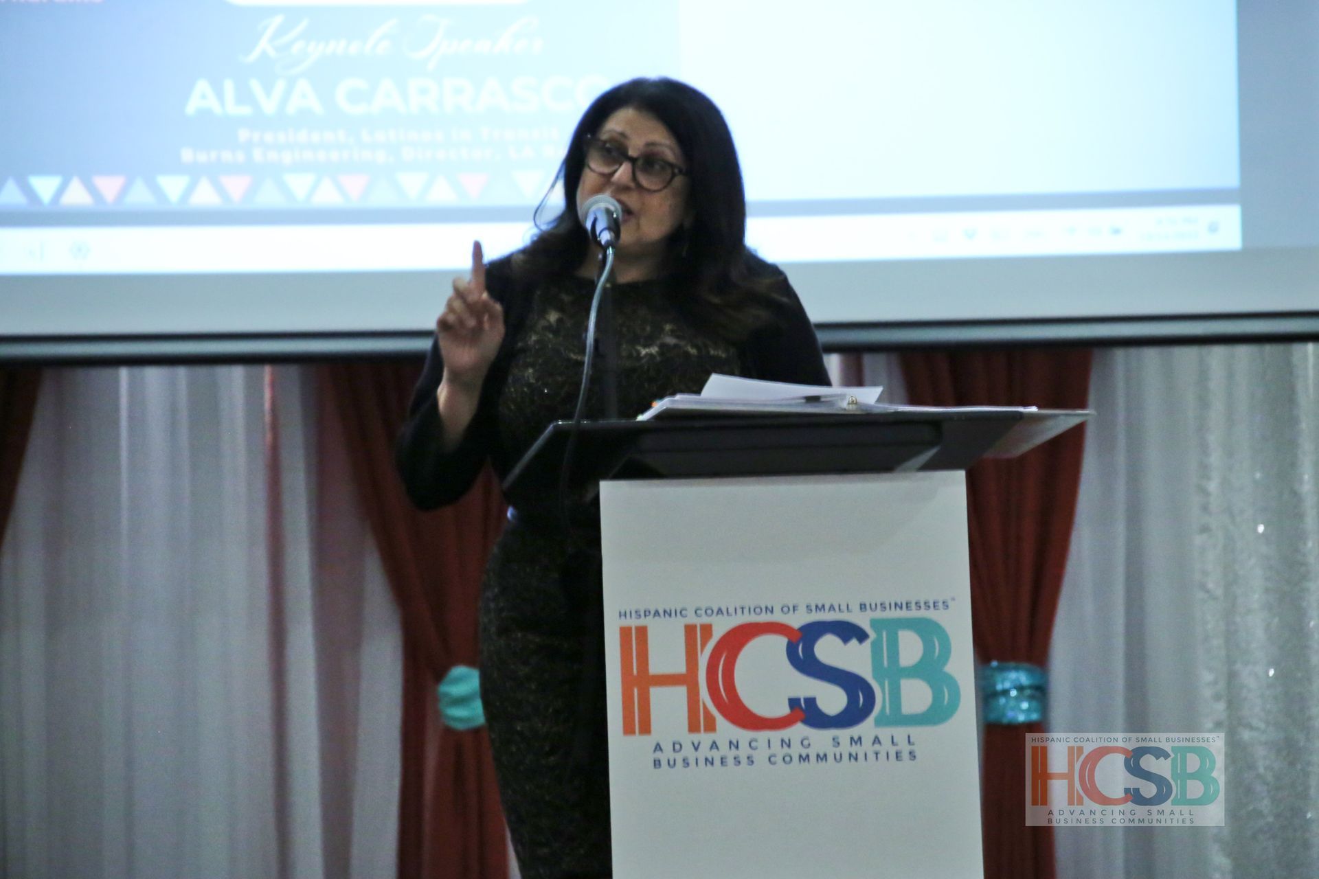 A woman stands at a podium that says hcsb on it