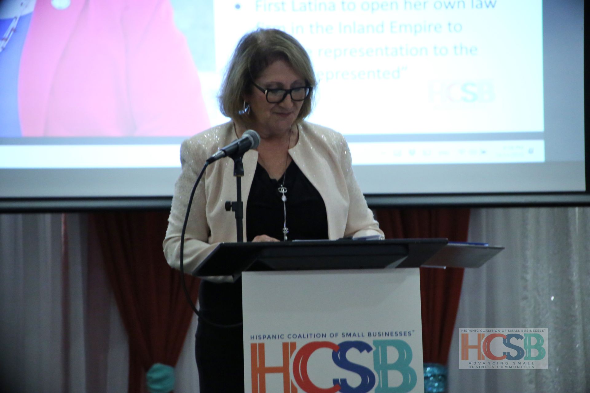 A woman is standing at a podium speaking into a microphone.