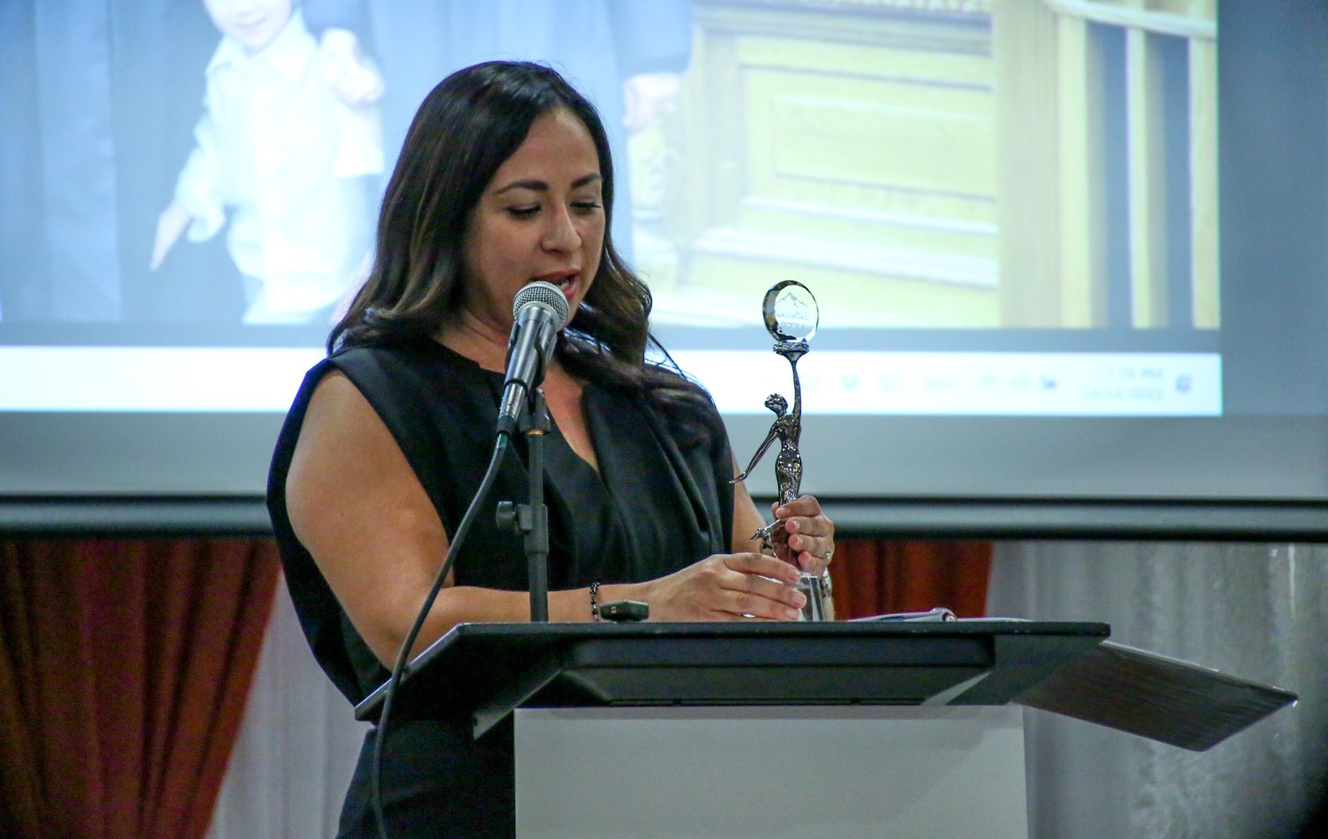 A woman is standing at a podium speaking into a microphone.