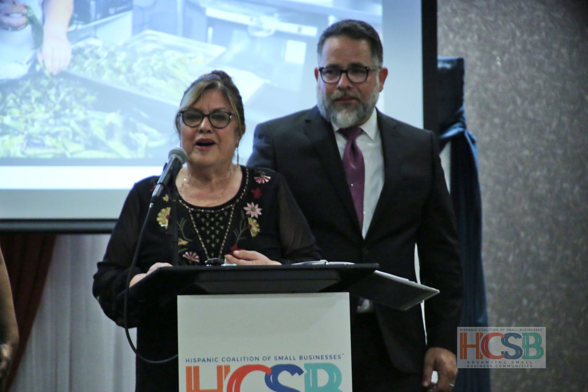 A man and a woman are standing at a podium that says hcsb