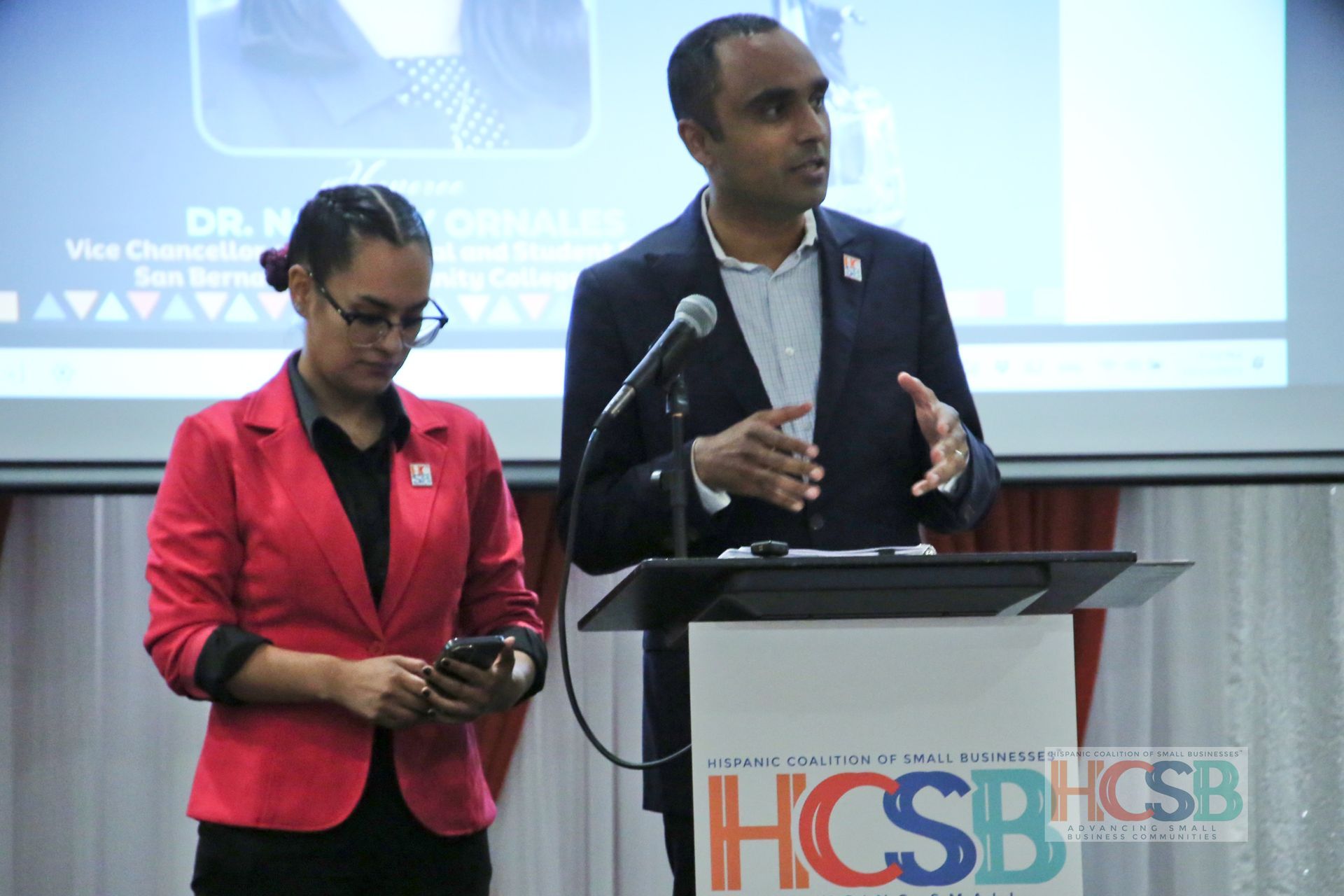 A man and a woman are standing at a podium with hcsb on it