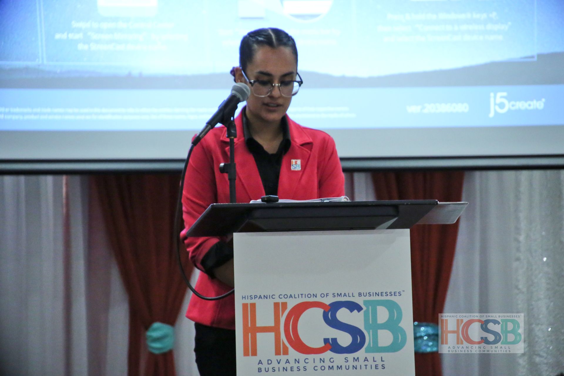 A woman stands at a podium that says hcsb