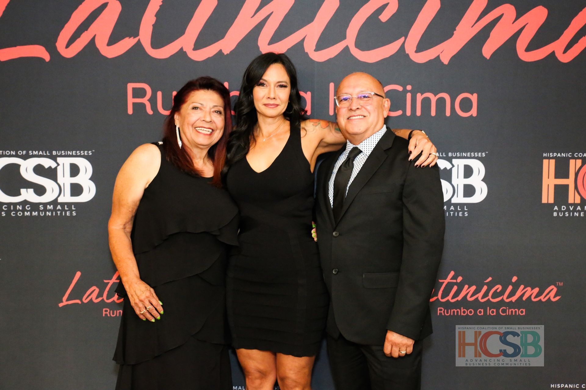 Three people posing for a picture in front of a sign that says csb