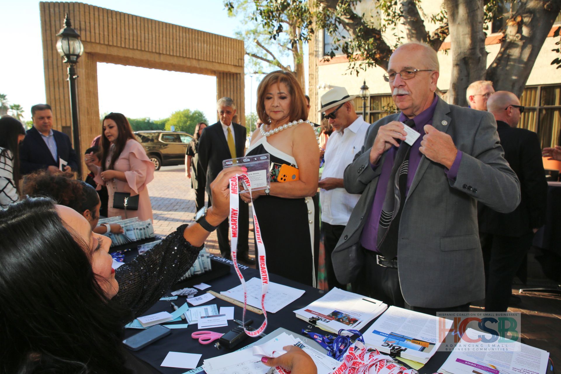 A woman is giving a lanyard to a man at a table