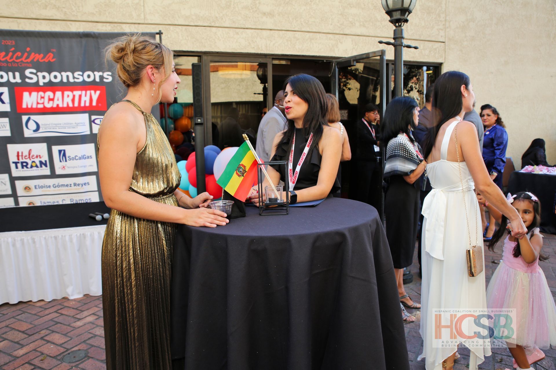 A group of women are standing around a table in front of a sign that says sponsors mccarthy