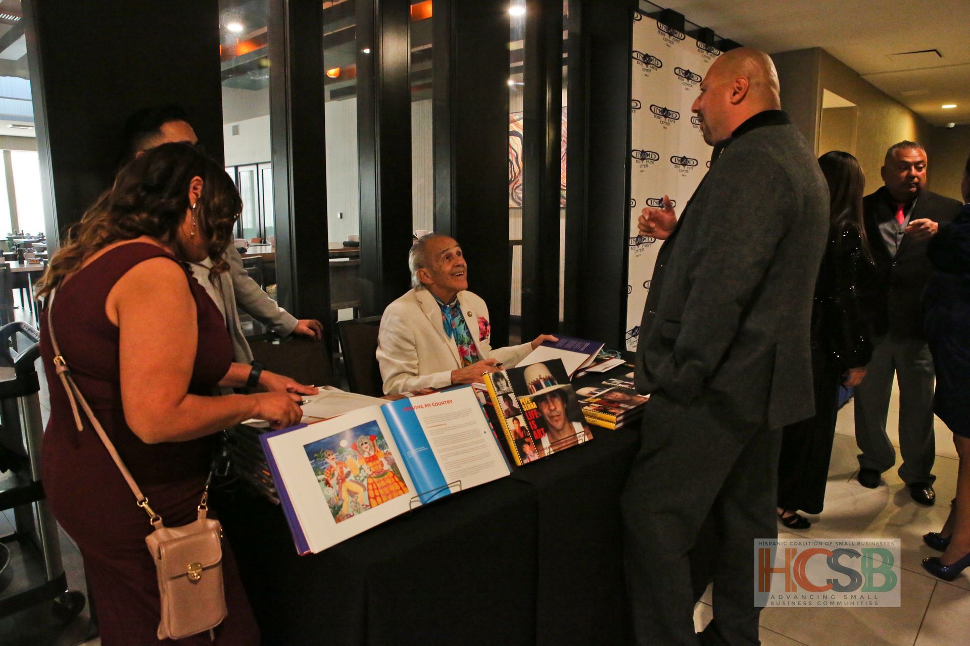 A group of people are standing around a table with a sign that says hcsb on it.