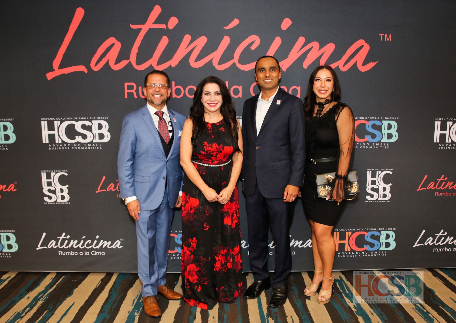A group of people are posing for a picture in front of a wall that says latincima