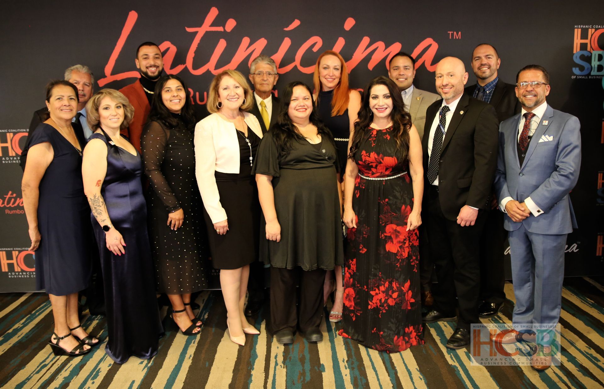A group of people are posing for a picture in front of a wall that says latincima