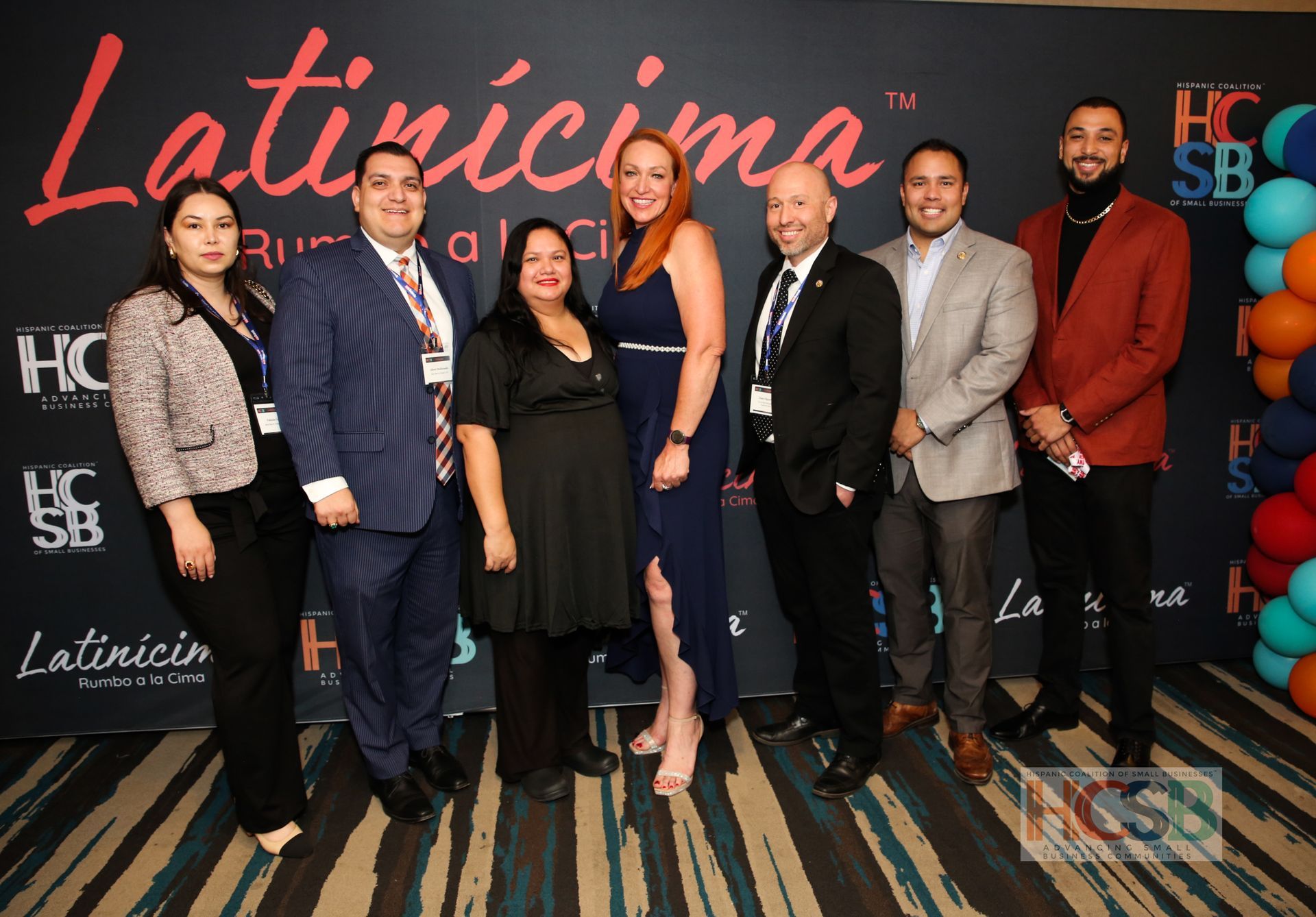 A group of people are posing for a picture in front of a wall that says latincima