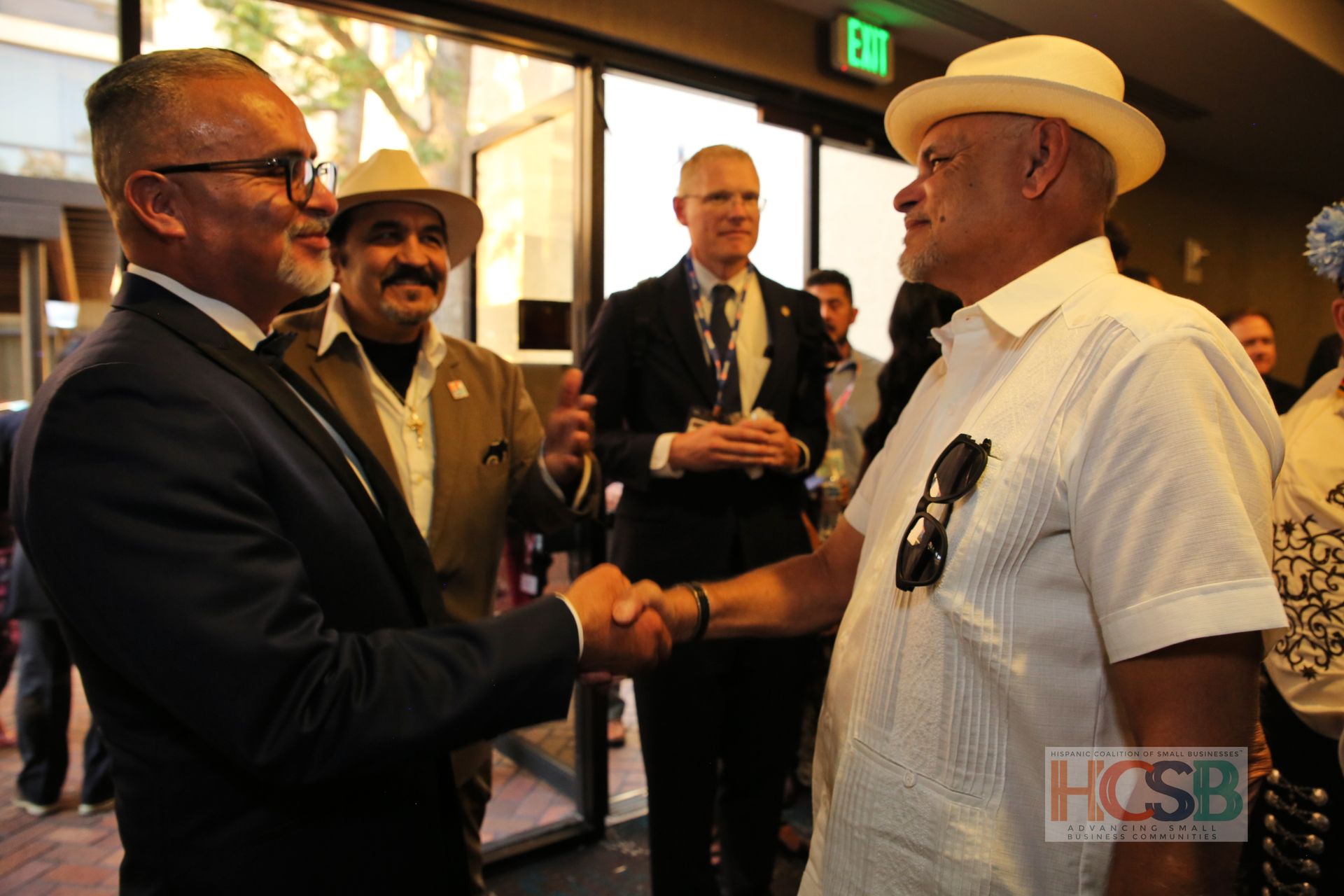 A man in a hat shakes hands with another man