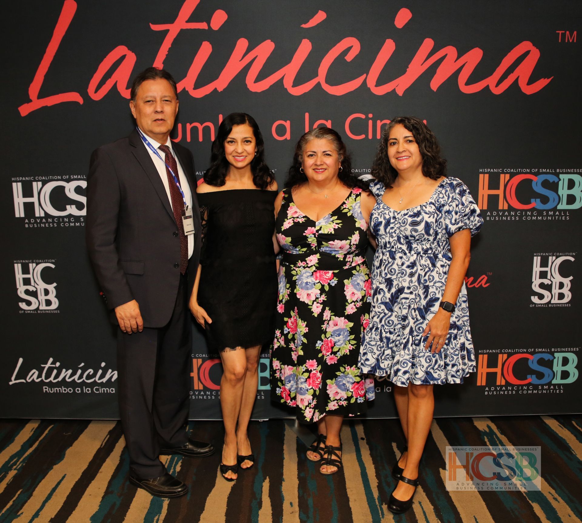 A group of people posing for a photo in front of a wall that says latincima