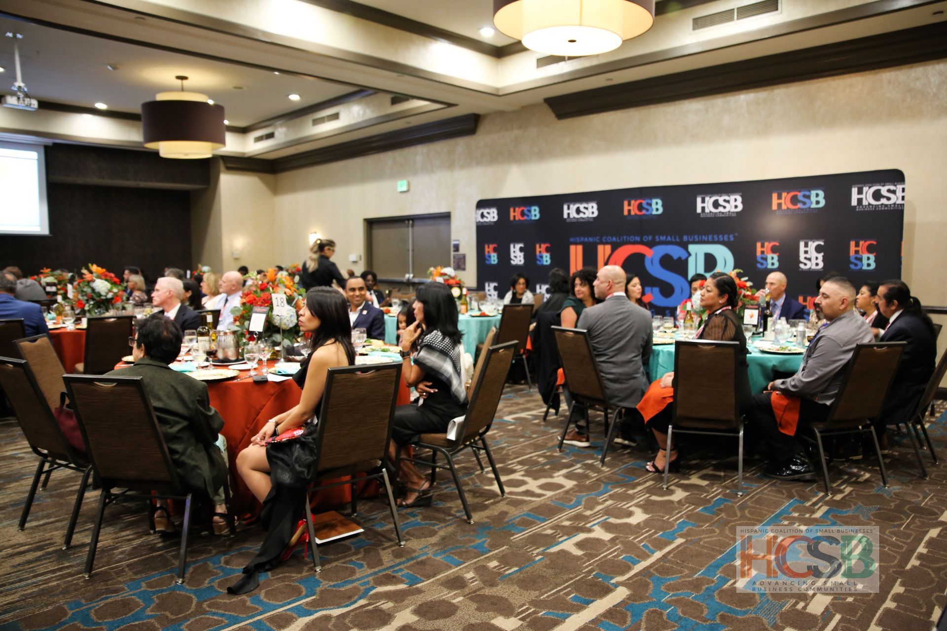 A group of people are sitting at tables in a large room.