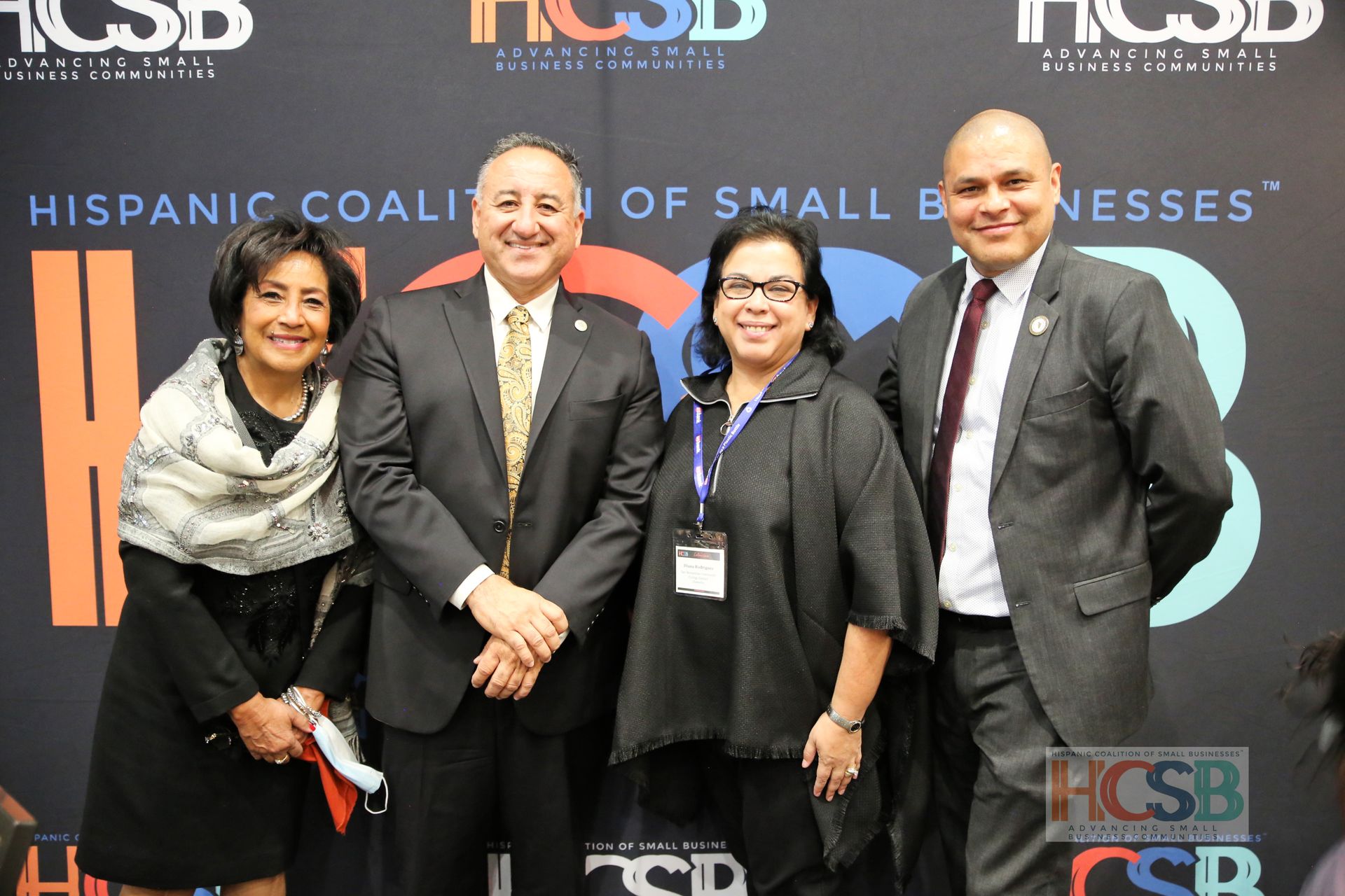 A group of people standing in front of a wall that says hispanic coalition of small businesses