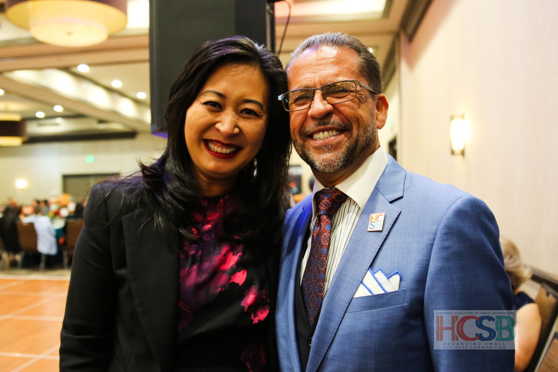 A man and a woman are posing for a picture and the man is wearing a suit and tie