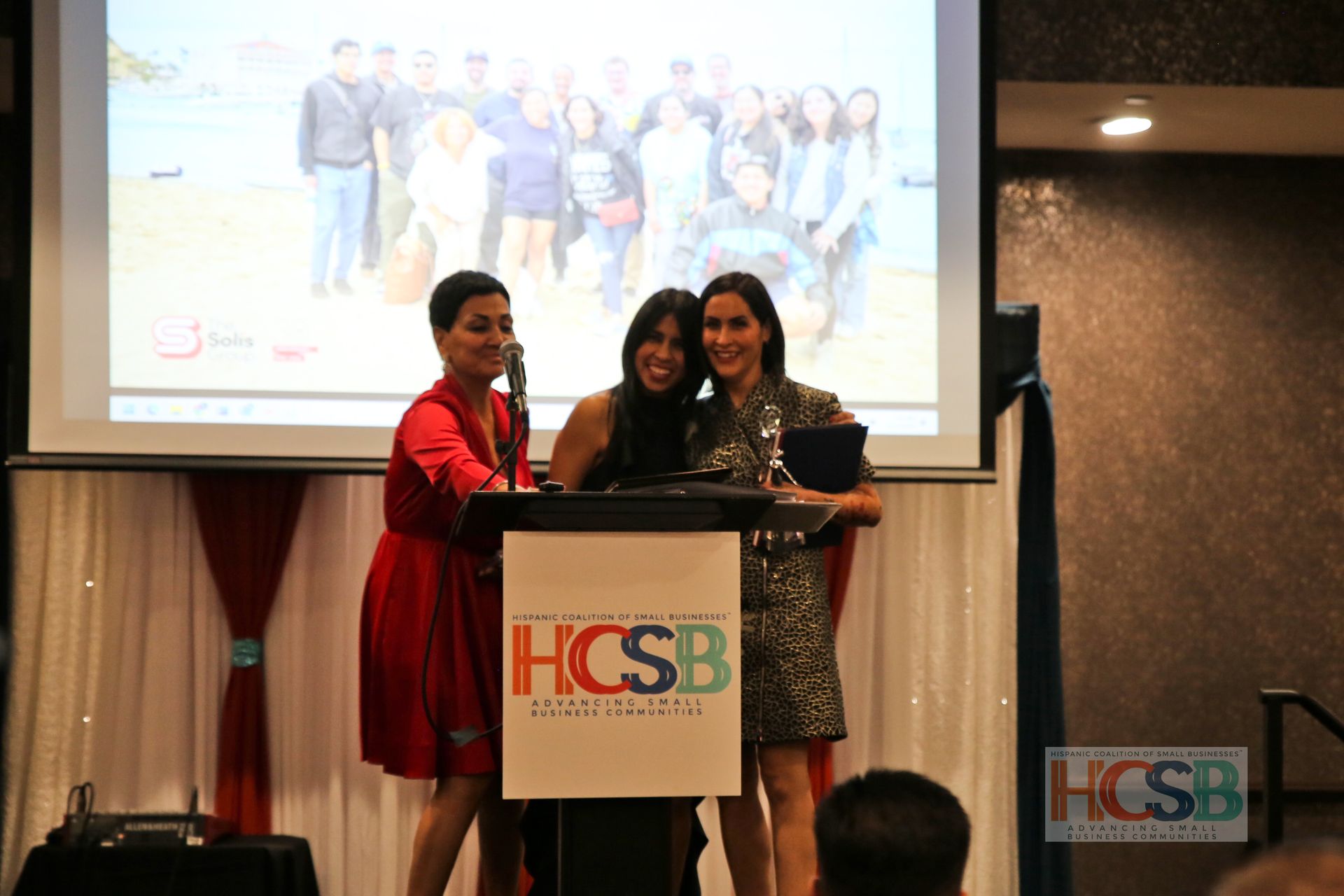 Three women standing behind a podium that says hcsb