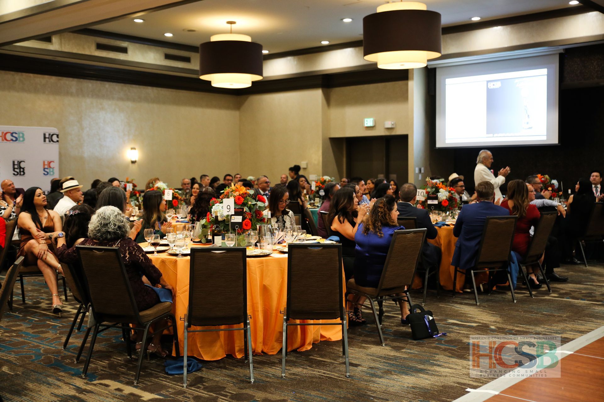 A large group of people are sitting at tables in a large room.