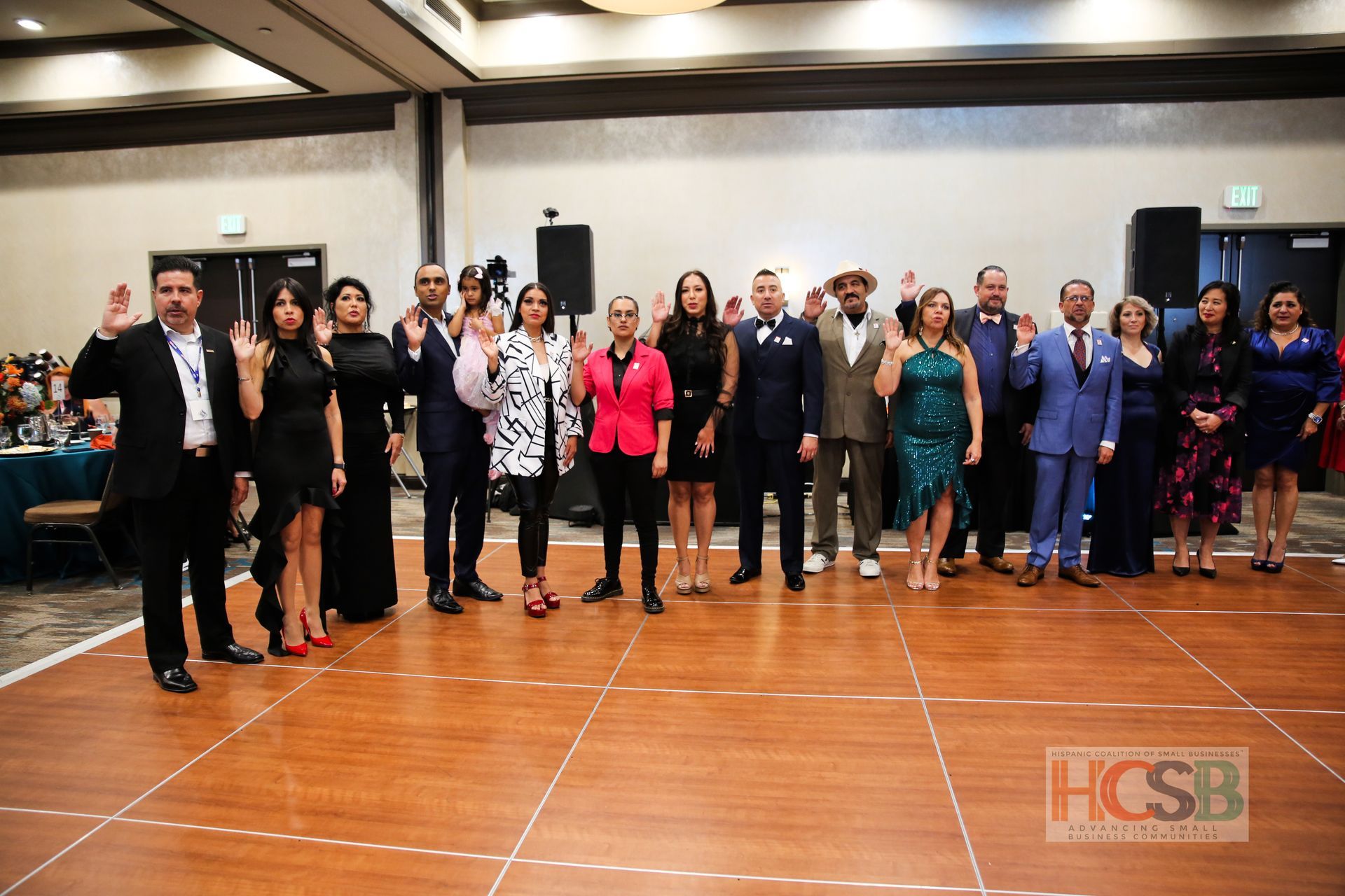 A group of people are standing on a wooden dance floor.
